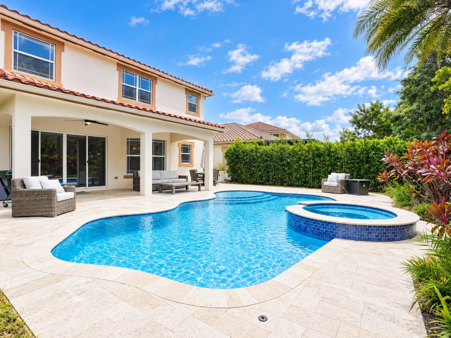 8601 Waterside Court, Parkland, FL 33076 Covered lanai featuring a stone-paver pool deck, freeform swimming pool, and tiled raised spa with mature hedge landscaping