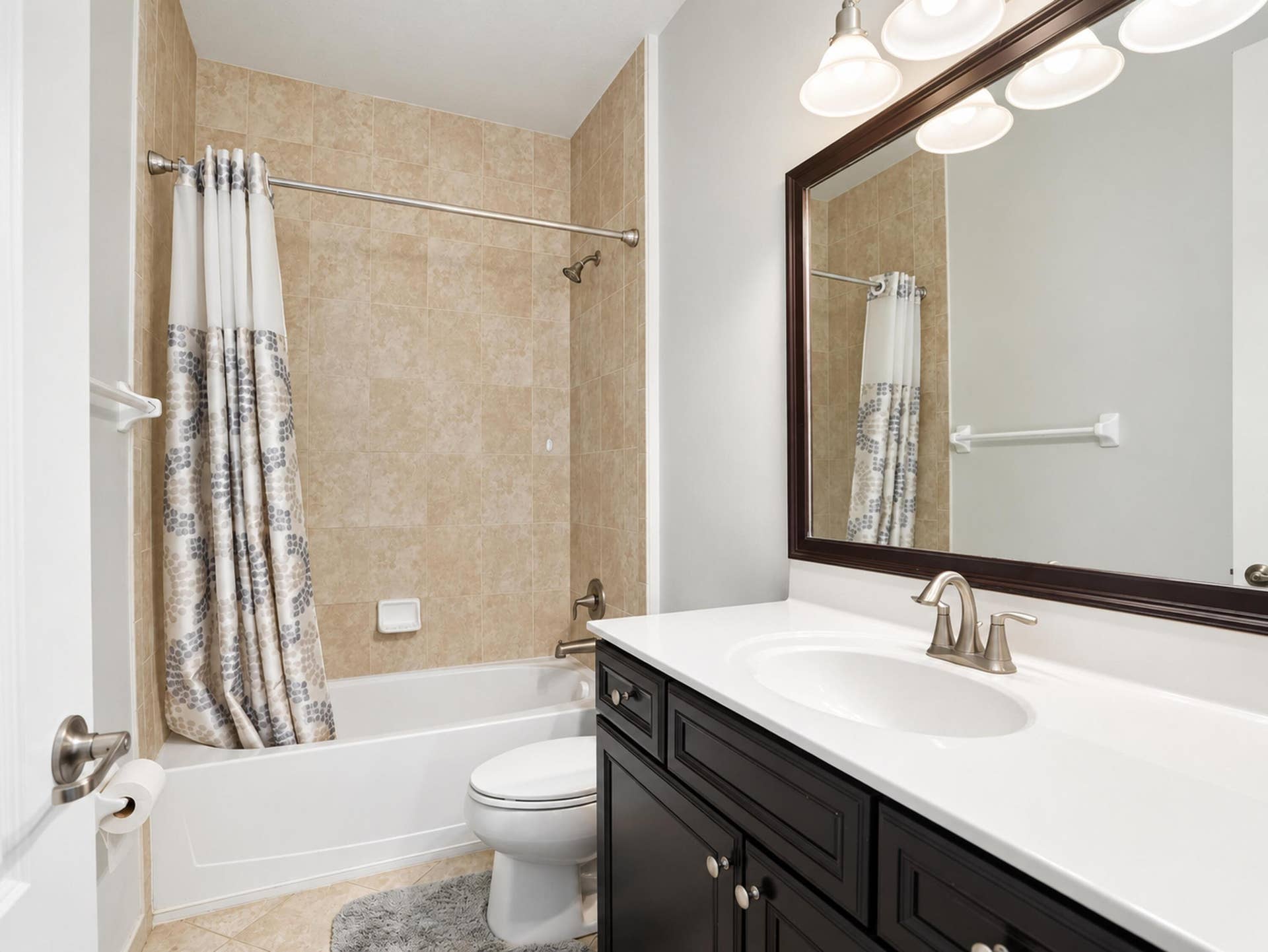 8601 Waterside Court, Parkland, FL 33076 Full bathroom featuring a dark wood vanity with a white countertop, an undermount sink with a brushed nickel faucet, a framed mirror, and a tub-shower combination with tiled surround