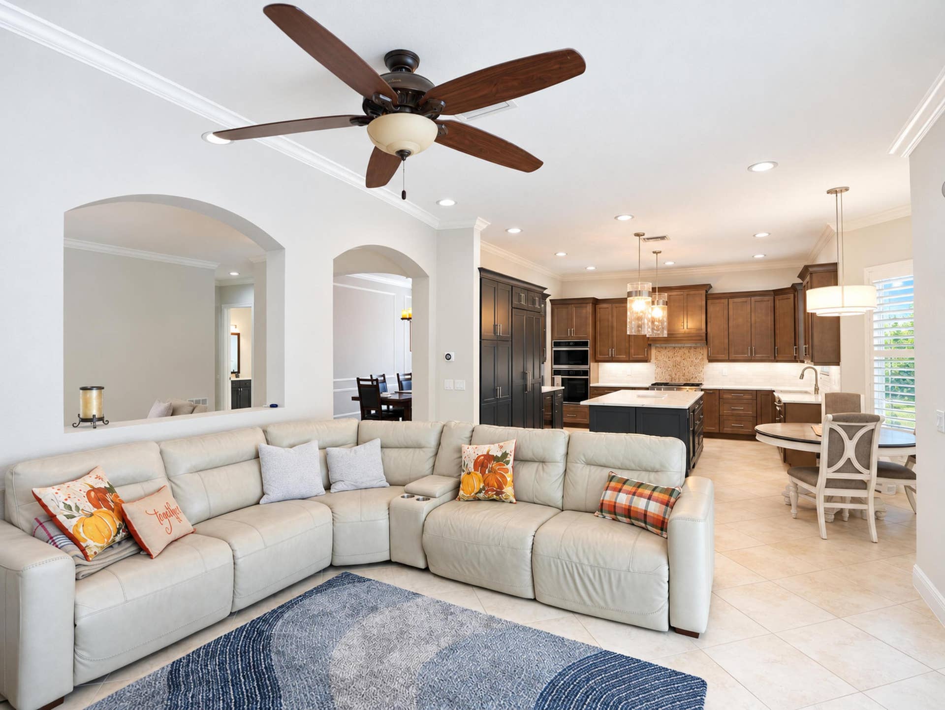 8601 Waterside Court, Parkland, FL 33076 Open-concept living space featuring arched wall cutouts, recessed lighting, multi-tone cabinetry, a central kitchen island with light-toned stone surfacing, and a ceiling fan with integrated lighting