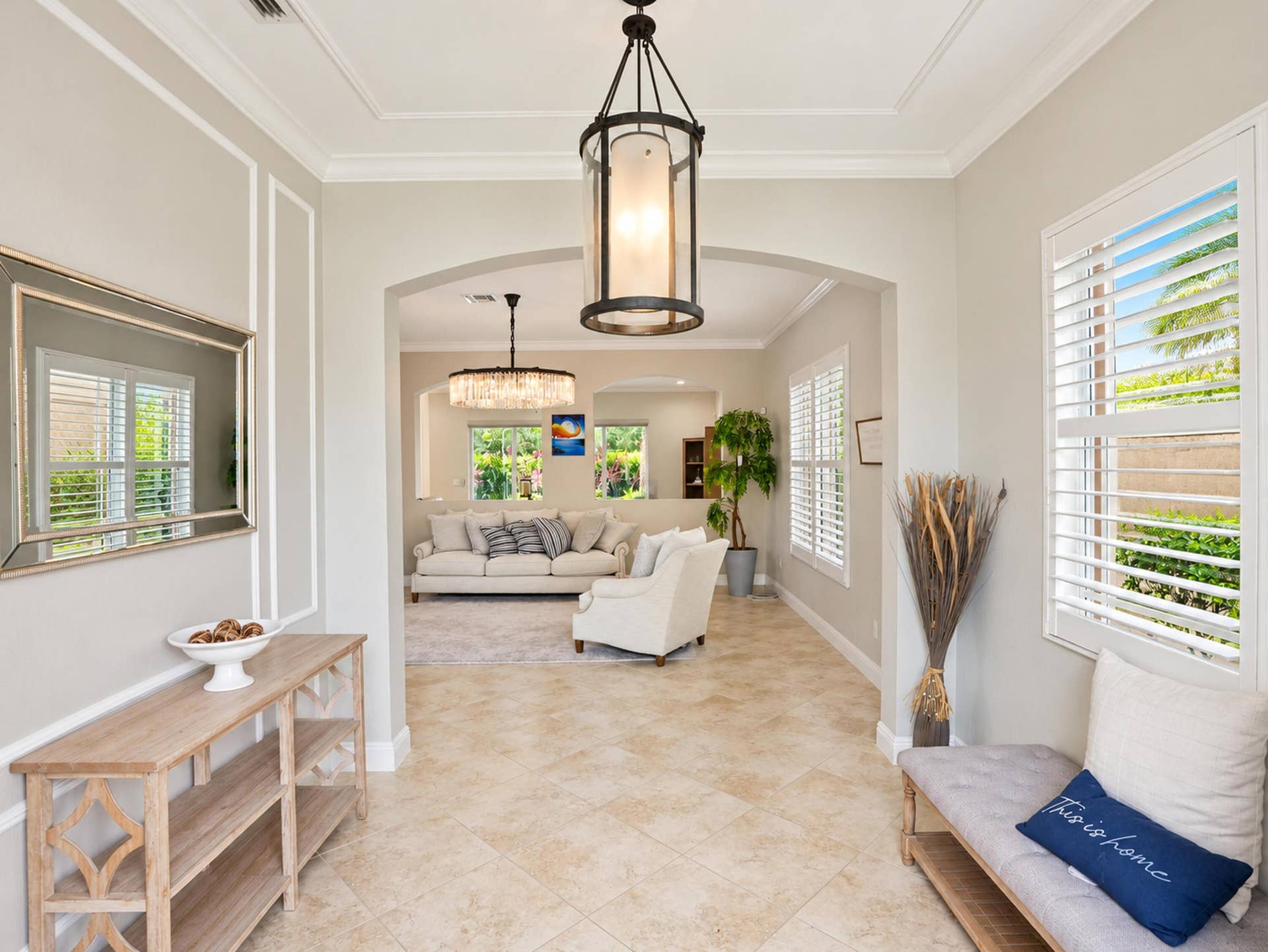 8601 Waterside Court, Parkland, FL 33076 Entryway featuring neutral-toned tile flooring, decorative wall molding, adjustable window shutters, and a prominent cylinder-style hanging light fixture