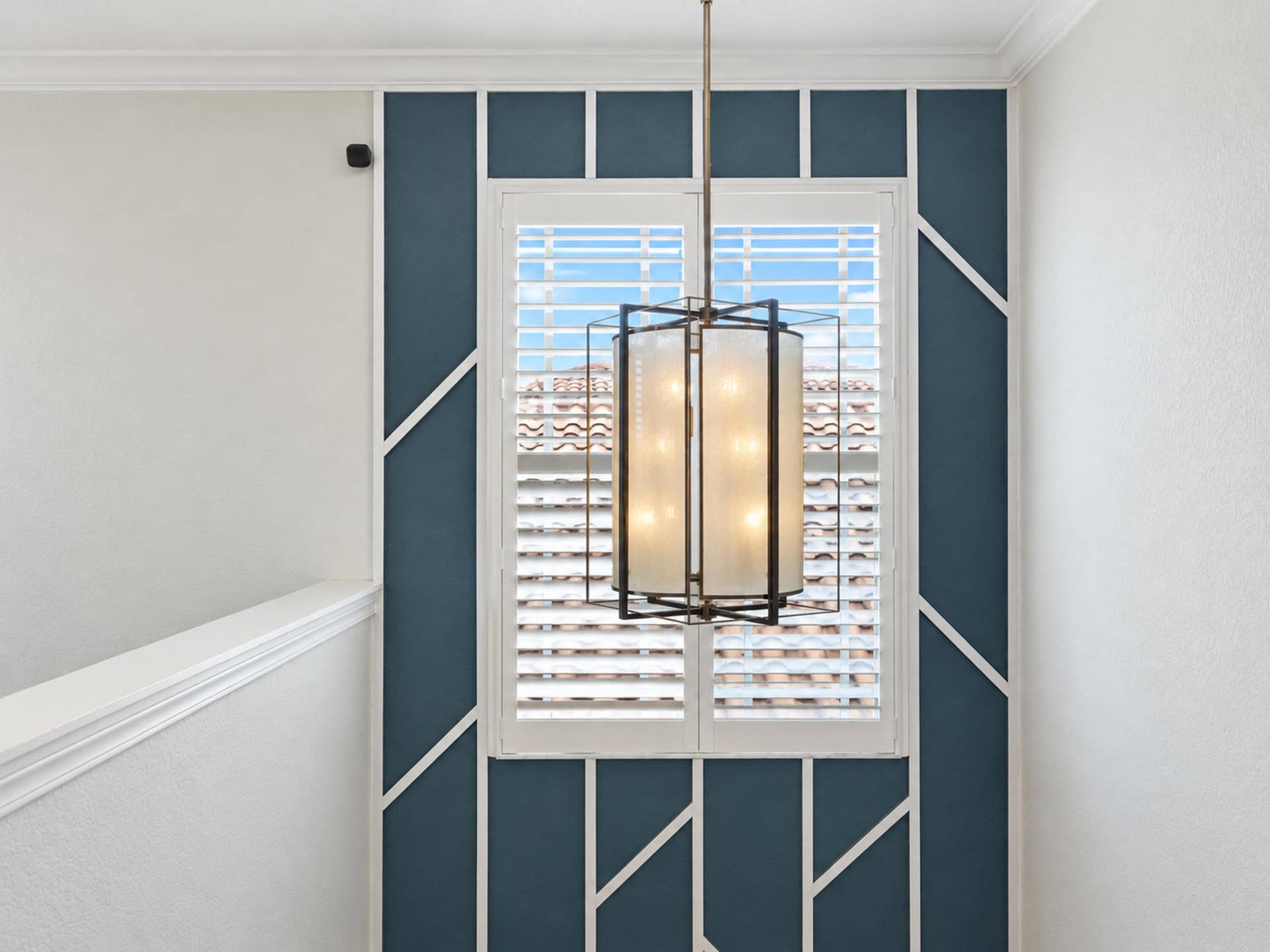 8601 Waterside Court, Parkland, FL 33076 Accent wall with geometric trim detailing, white plantation shutters, and a suspended multi-light pendant fixture