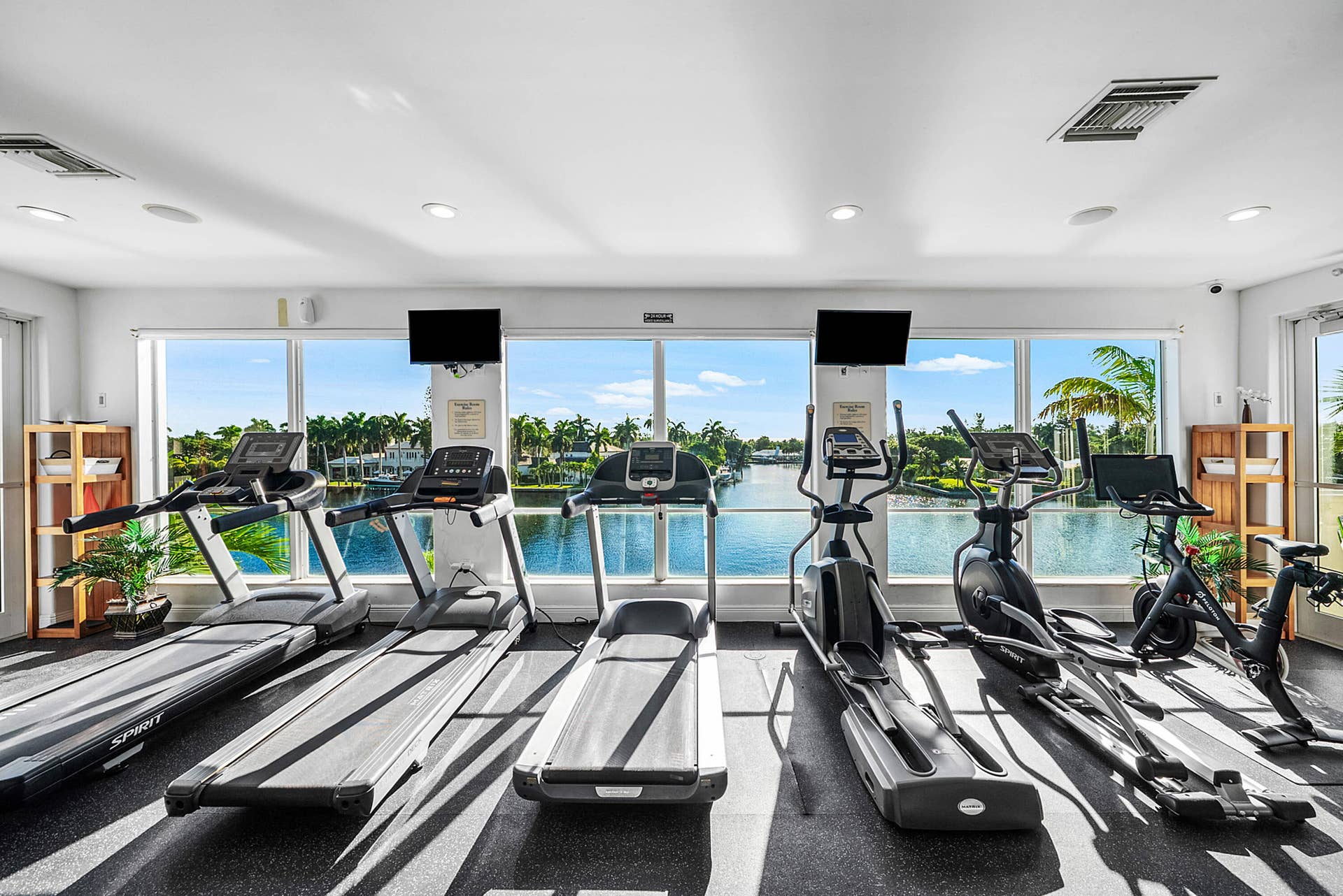Fitness center with floor-to-ceiling windows, recessed lighting, and water scenery