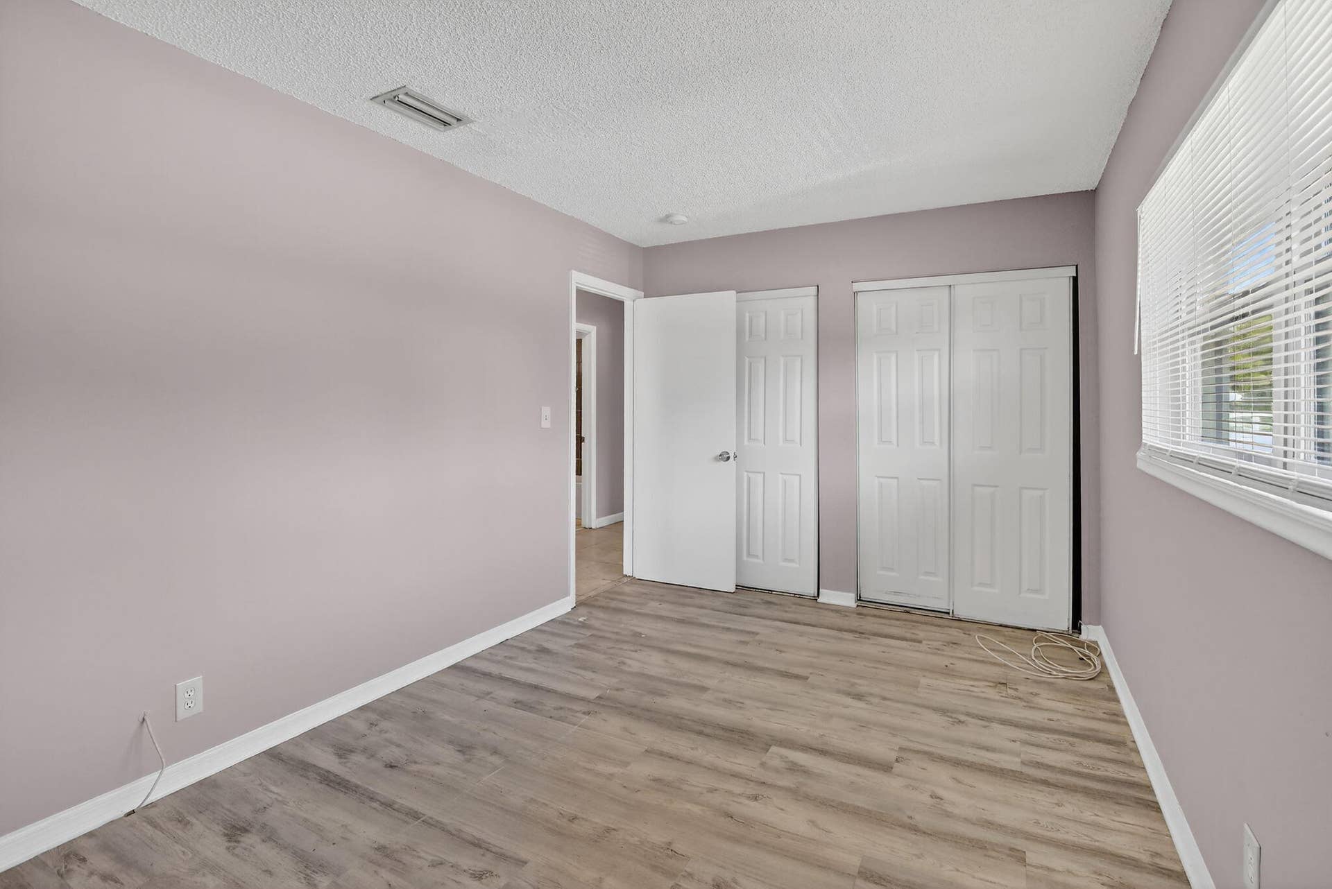 Interior room featuring wood-finish flooring, white paneled doors, and a sliding-door closet