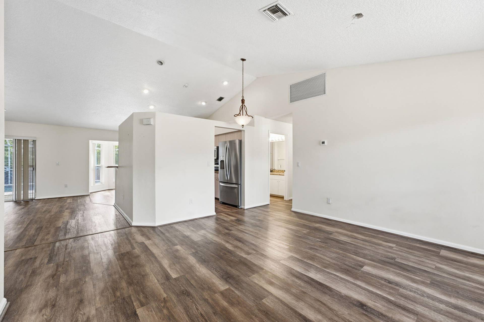 Vaulted ceilings, wood-finish flooring, stainless steel kitchen appliances, and decorative pendant lighting