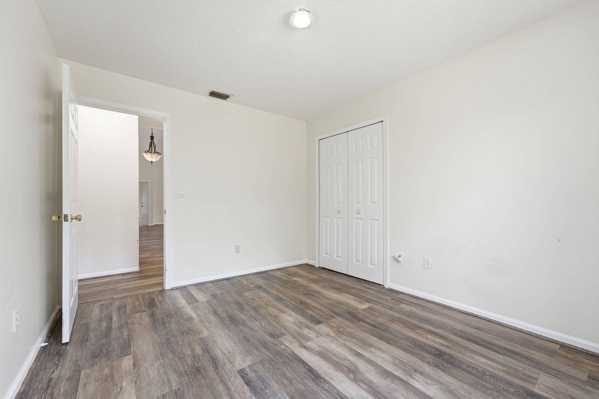 Neutral-toned interior featuring wood-finish flooring, a double-panel closet with white doors, and a flush-mount ceiling light fixture