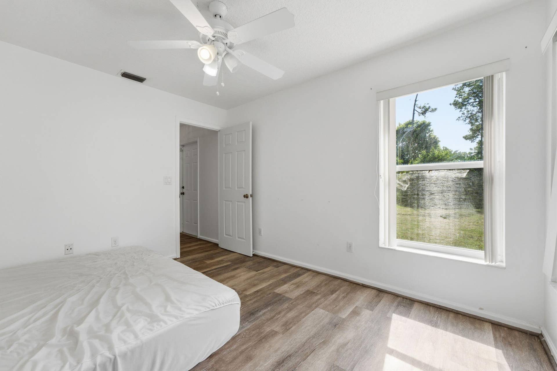 Wood-finish flooring, ceiling fan with integrated lighting, and neutral wall tones