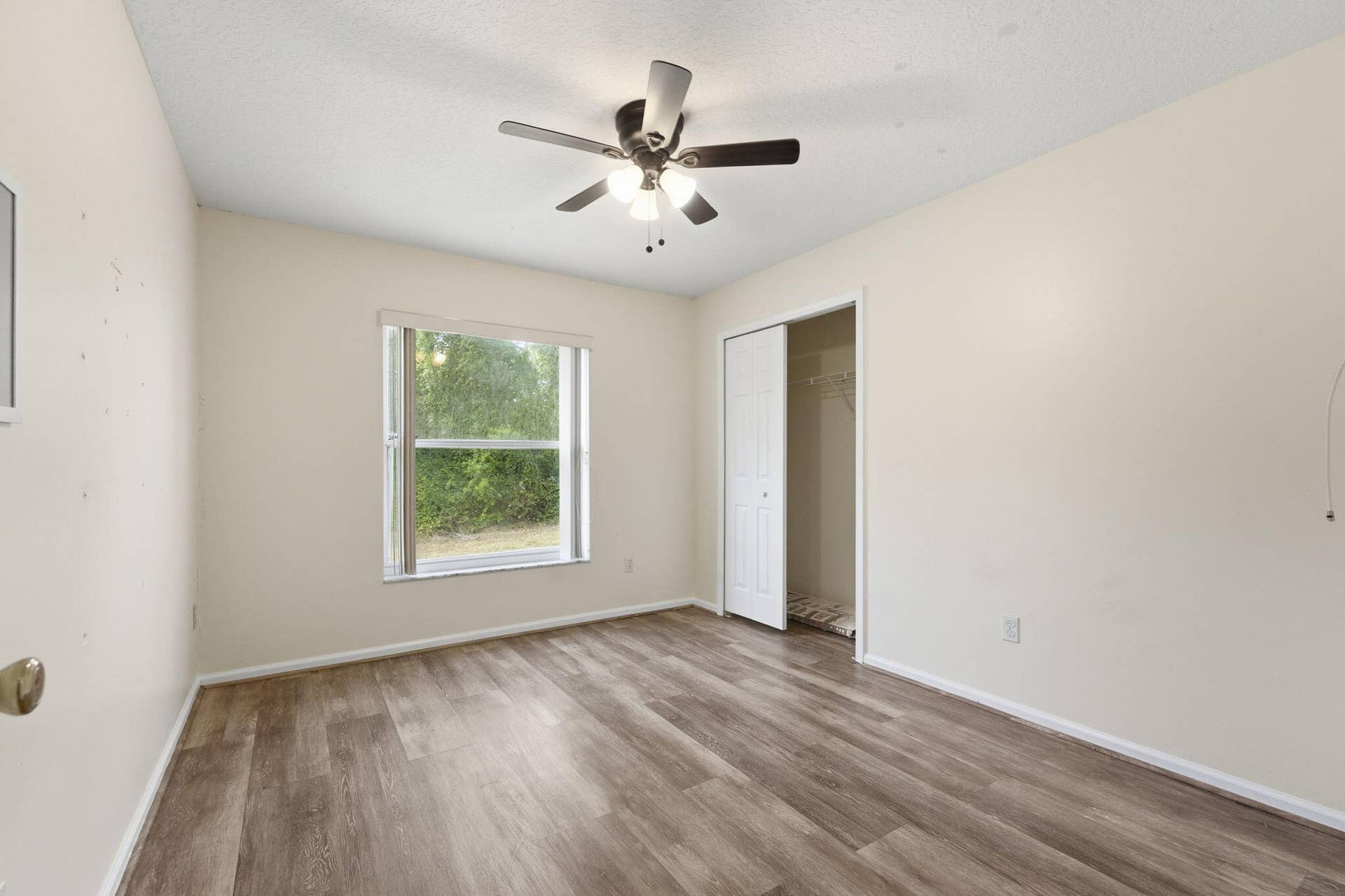 Wood-finish flooring, ceiling fan with integrated lighting, window with horizontal blinds, and closet with sliding door