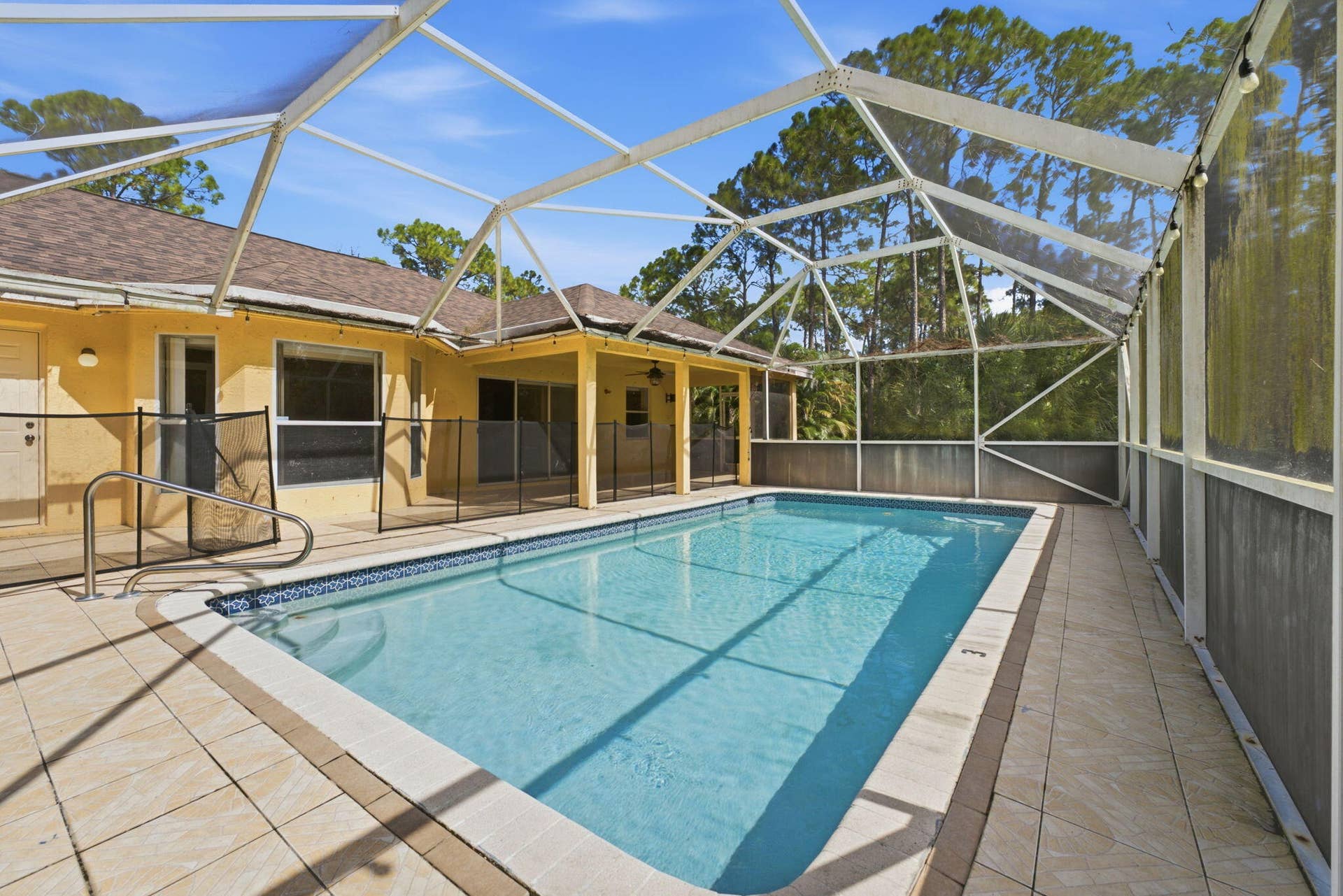 Screened-in outdoor enclosure featuring a swimming pool, tile decking, and a covered lanai