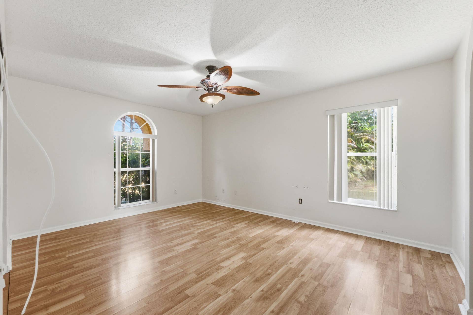 Wood-finish flooring, vaulted ceiling, arched window, and ceiling fan with integrated lighting