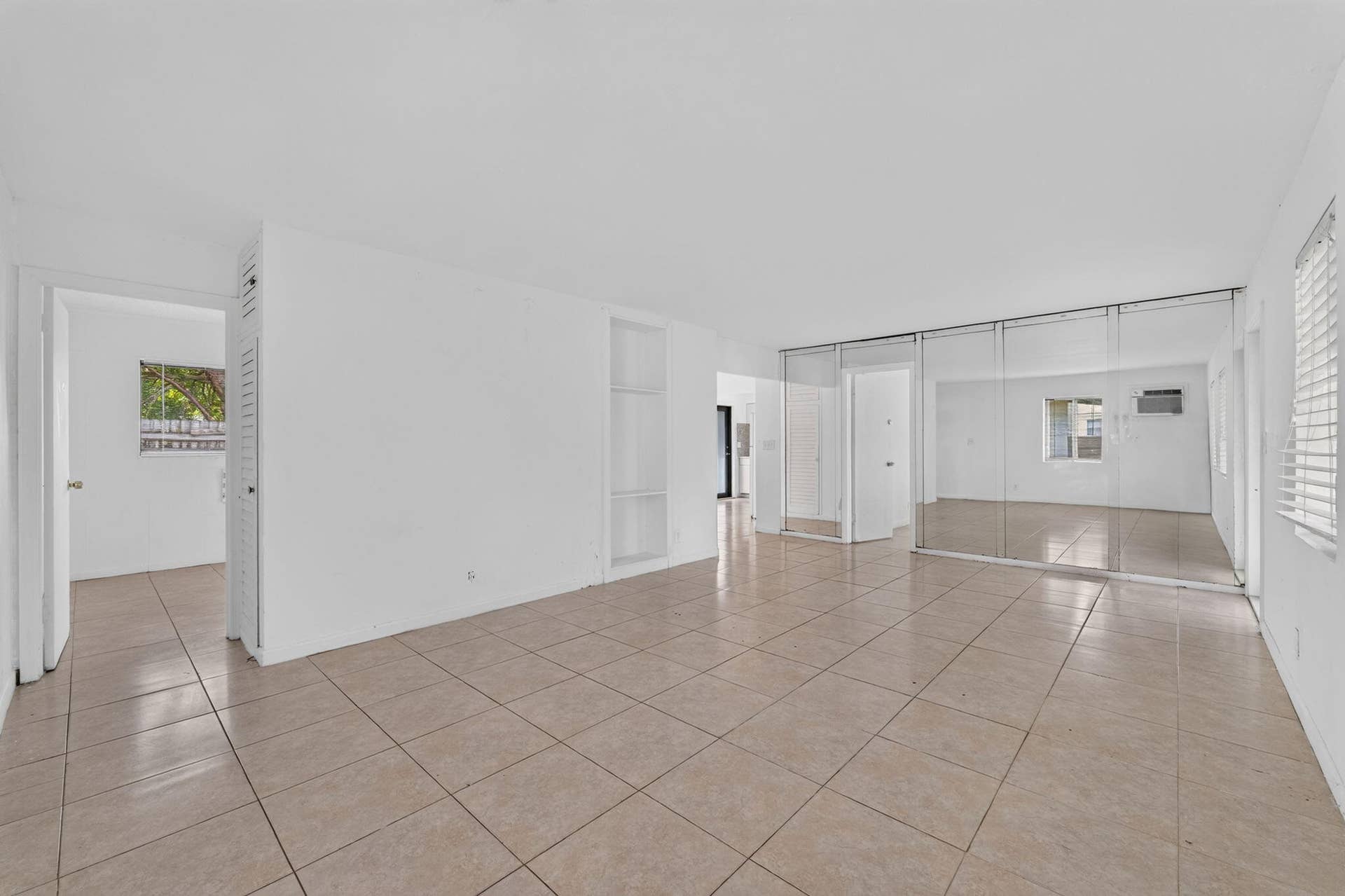 1224 NE 5TH Avenue, Fort Lauderdale, FL 33304 Interior space featuring tile flooring, built-in shelving, and floor-to-ceiling mirrored closet doors