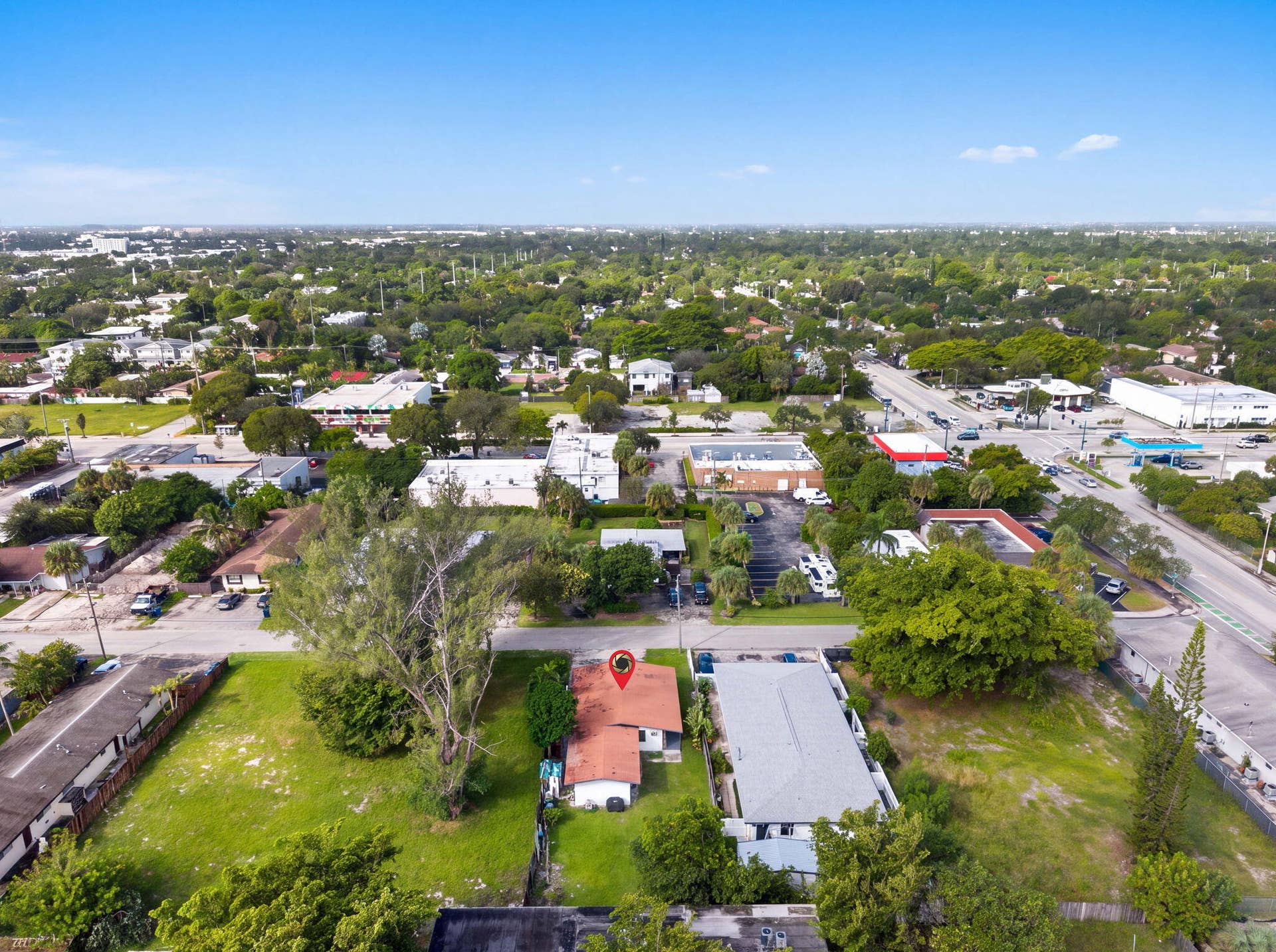 1224 NE 5TH Avenue, Fort Lauderdale, FL 33304 Aerial perspective featuring a single-story structure with a pitched roof, an expansive lawn, and mature trees situated on an oversized parcel