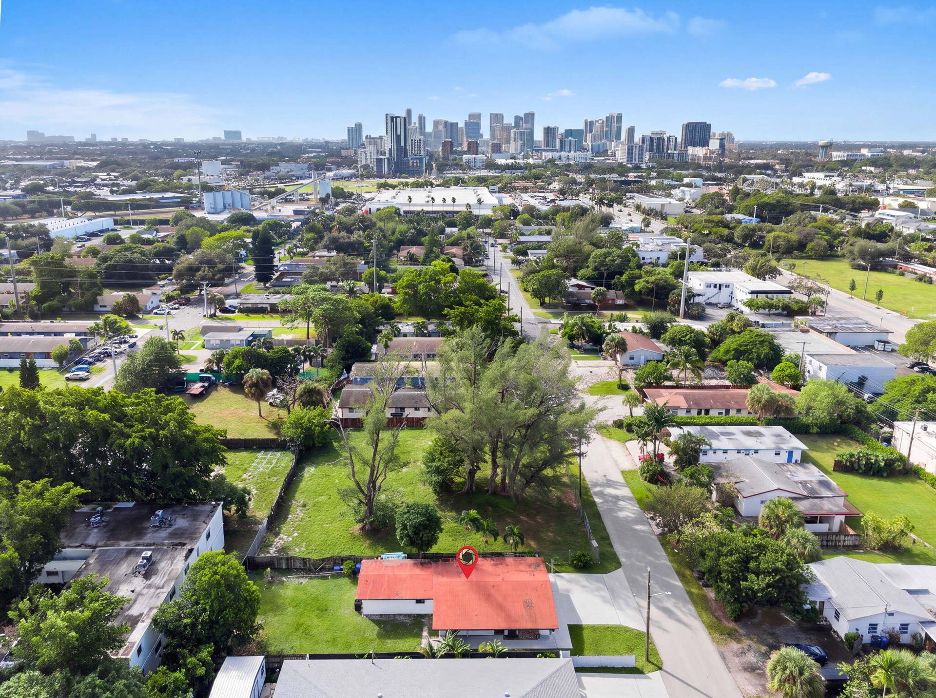 1224 NE 5TH Avenue, Fort Lauderdale, FL 33304 Aerial perspective featuring a red shingle roof, a spacious lot with mature trees, and a metropolitan skyline backdrop