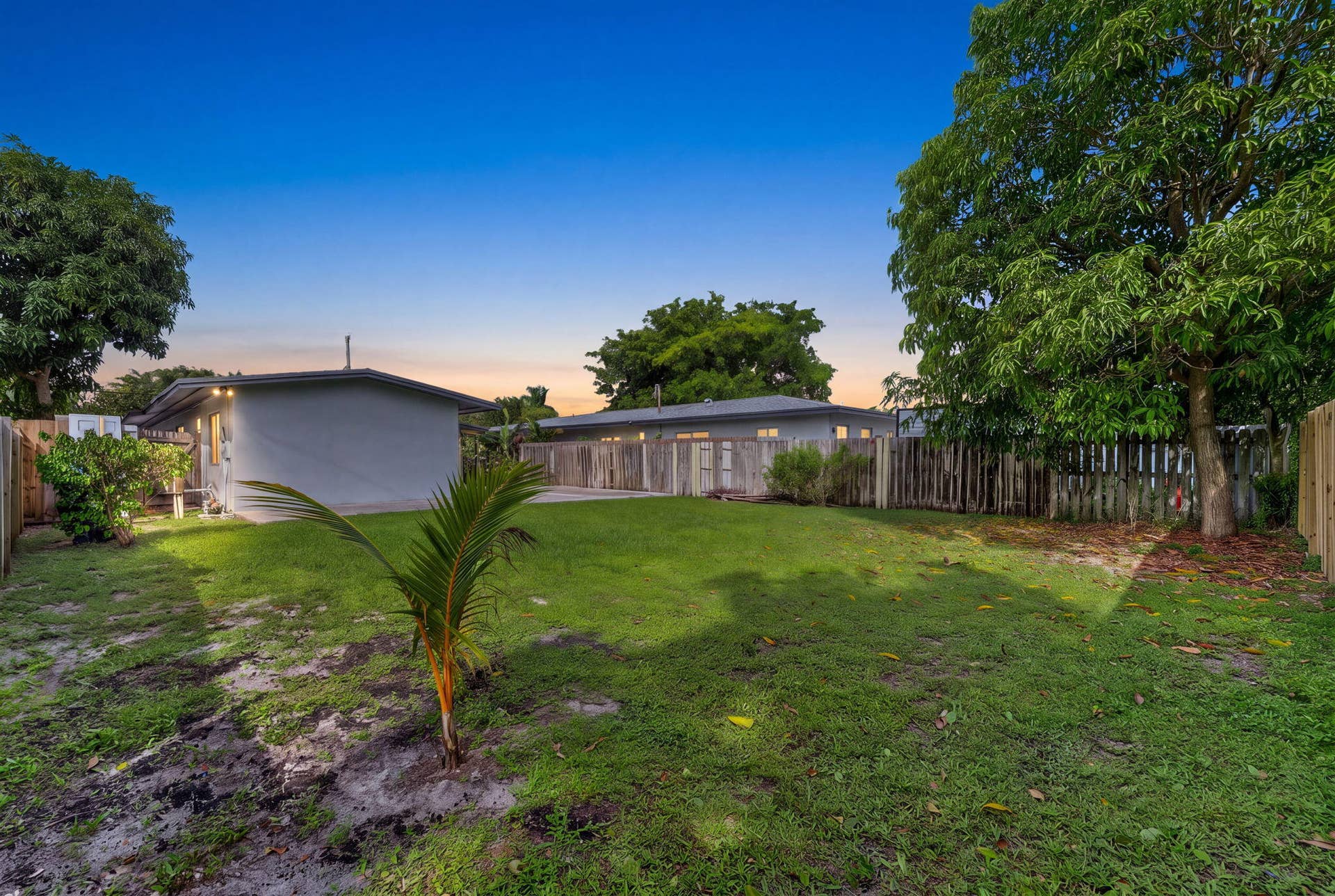 1224 NE 5TH Avenue, Fort Lauderdale, FL 33304 Expansive backyard featuring a level lawn, mature trees, concrete patio space, and wood-style perimeter fencing