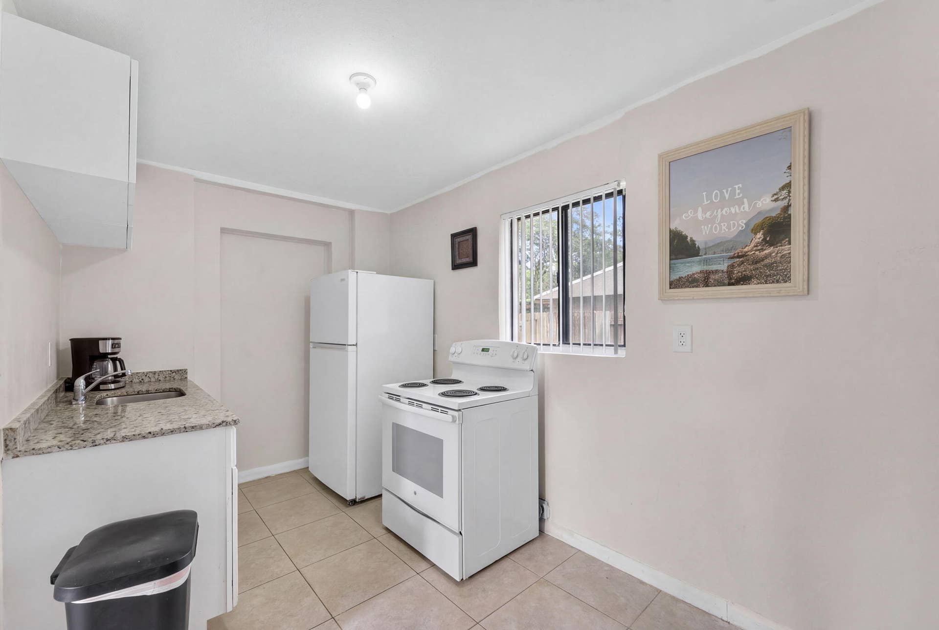 1224 NE 5TH Avenue, Fort Lauderdale, FL 33304 Kitchen featuring stone-finish countertops, tile flooring, white cabinetry, and a window with horizontal blinds