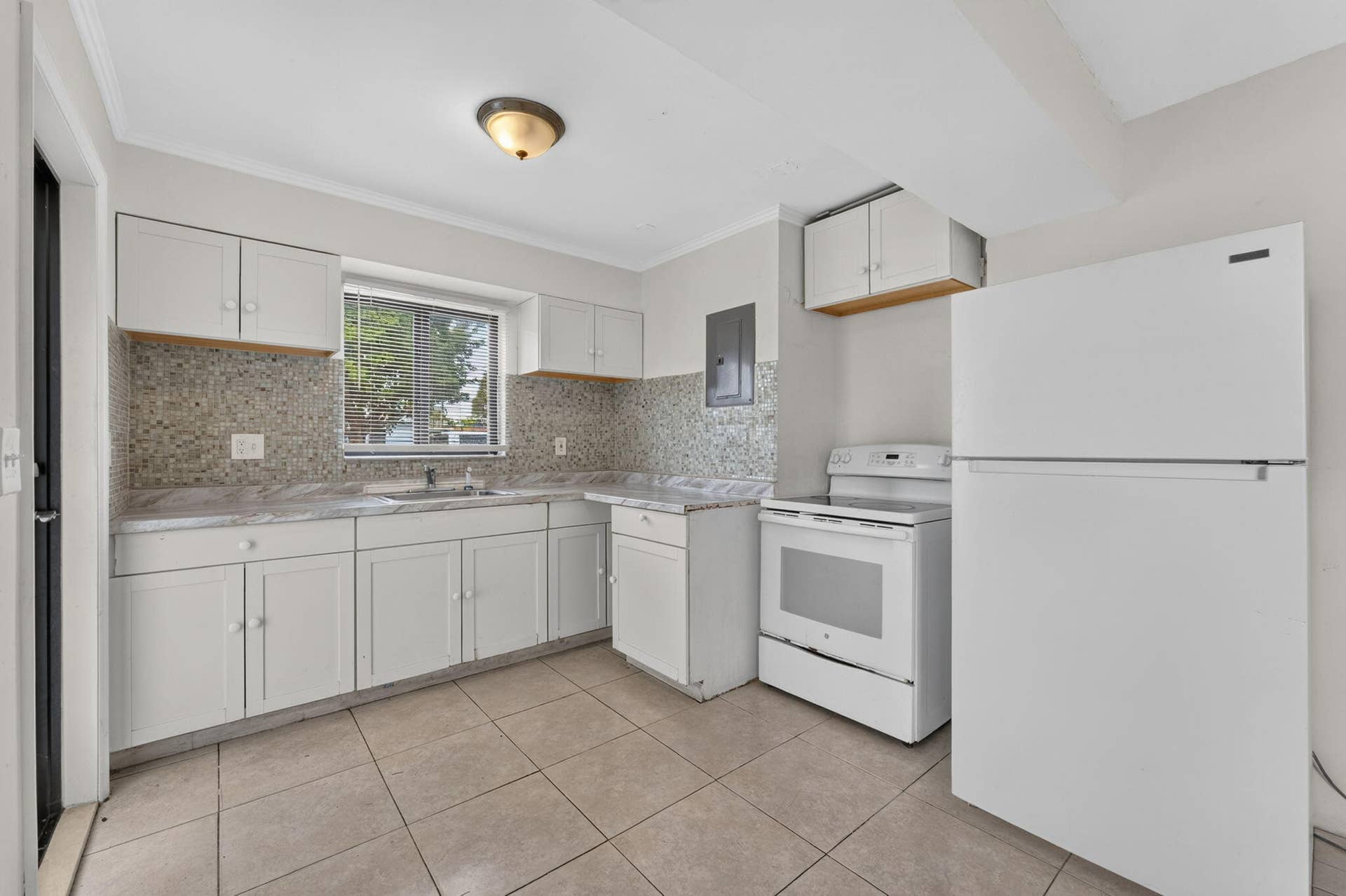 1224 NE 5TH Avenue, Fort Lauderdale, FL 33304 Kitchen featuring white cabinetry, stone-texture backsplash, neutral-toned tile flooring, and white appliance suite