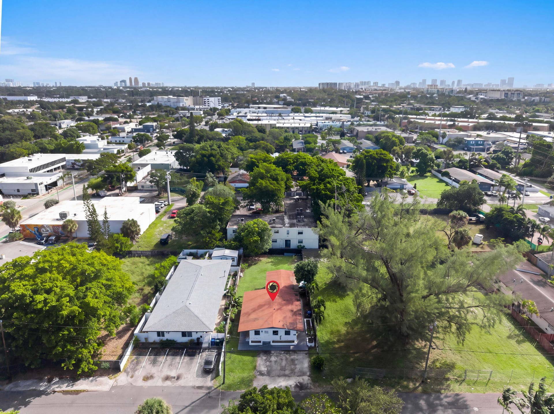 1224 NE 5TH Avenue, Fort Lauderdale, FL 33304 Aerial perspective of a detached property featuring a pitched roof, paved driveway, expansive lawn, and mature trees