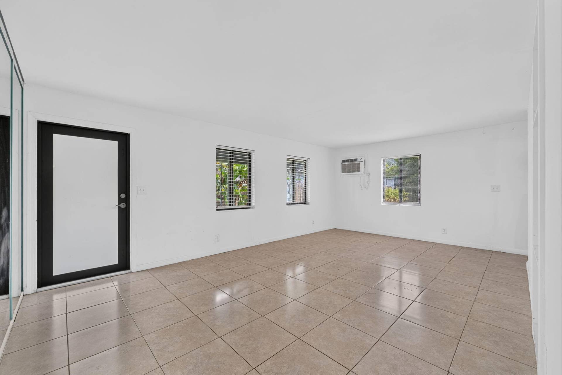 1224 NE 5TH Avenue, Fort Lauderdale, FL 33304 Neutral-toned tile flooring, light-filled interior with white walls, black-framed exterior door, and multi-pane windows