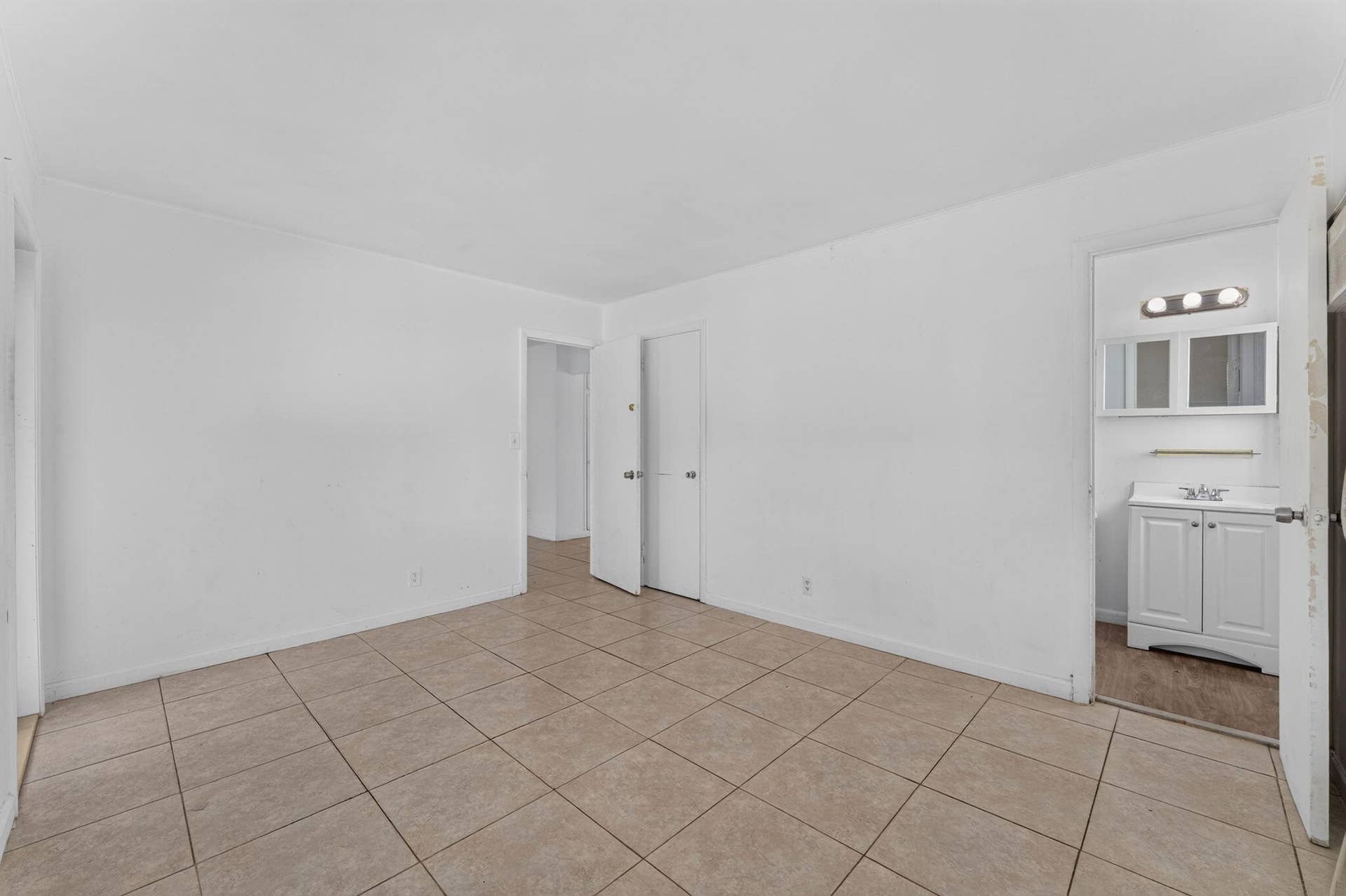 1224 NE 5TH Avenue, Fort Lauderdale, FL 33304 Neutral-toned tile flooring throughout with a dual-door closet and access to a bathroom featuring a white vanity cabinet and a wall-mounted mirrored medicine cabinet