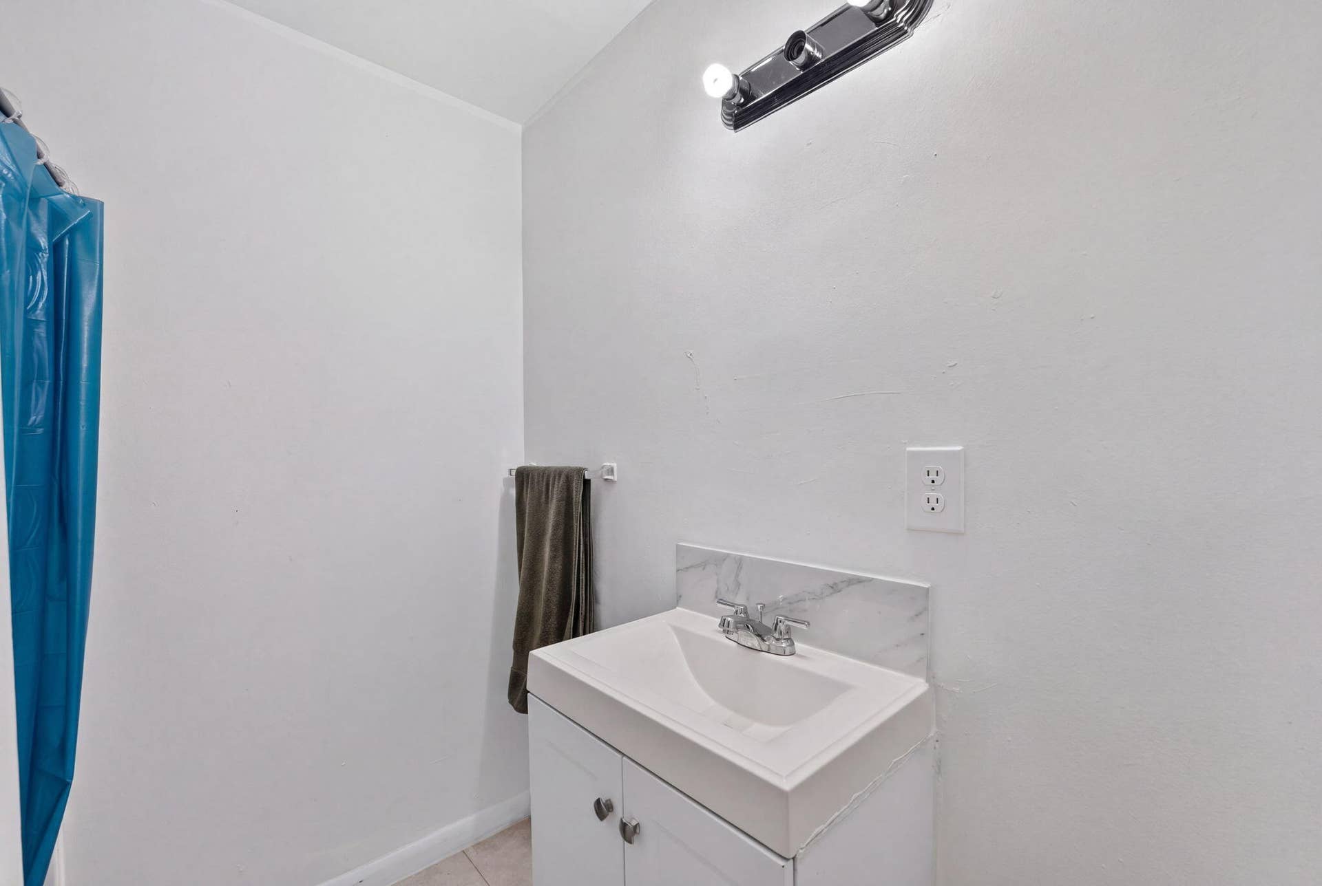 1224 NE 5TH Avenue, Fort Lauderdale, FL 33304 Bathroom vanity featuring a white cabinet, integrated sink, stone-finish backsplash, and a multi-bulb wall-mounted light fixture