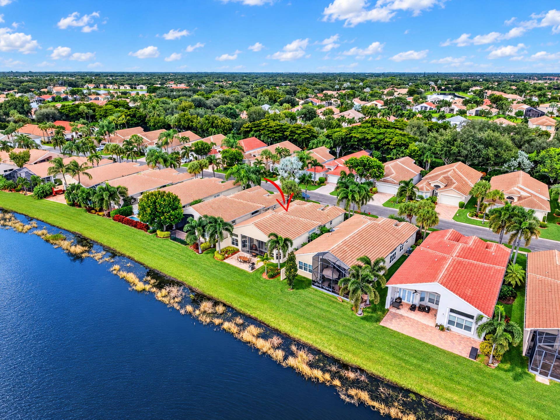 6874 Venidita Beach Drive, Delray Beach, FL 33446 Waterfront property featuring a tile roof, paved patio, and established tropical landscaping