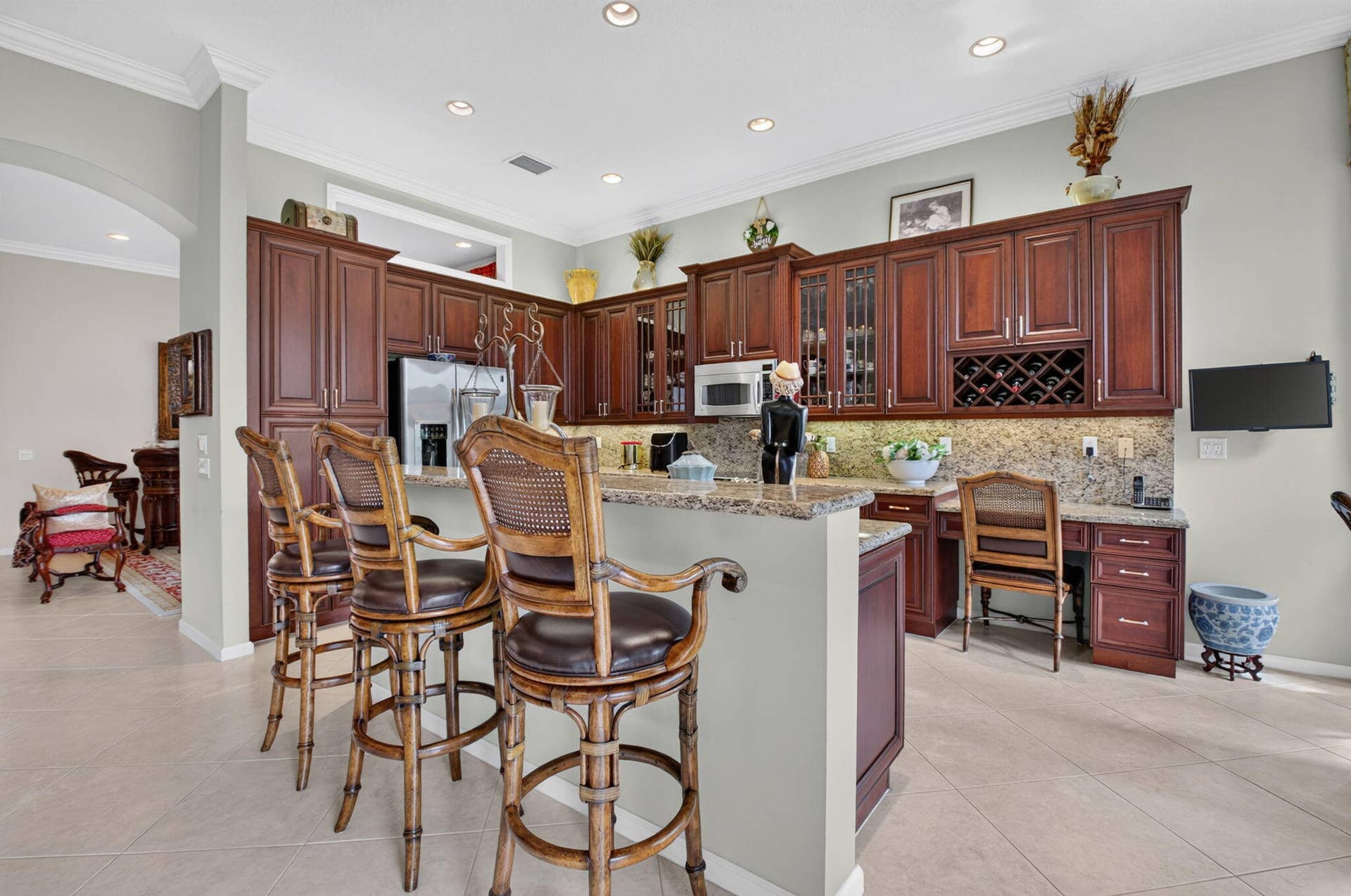6874 Venidita Beach Drive, Delray Beach, FL 33446 Kitchen featuring recessed lighting, stone-surface countertops, built-in cabinetry with glass-front display panels and integrated wine storage, and a breakfast bar with stone-surface top