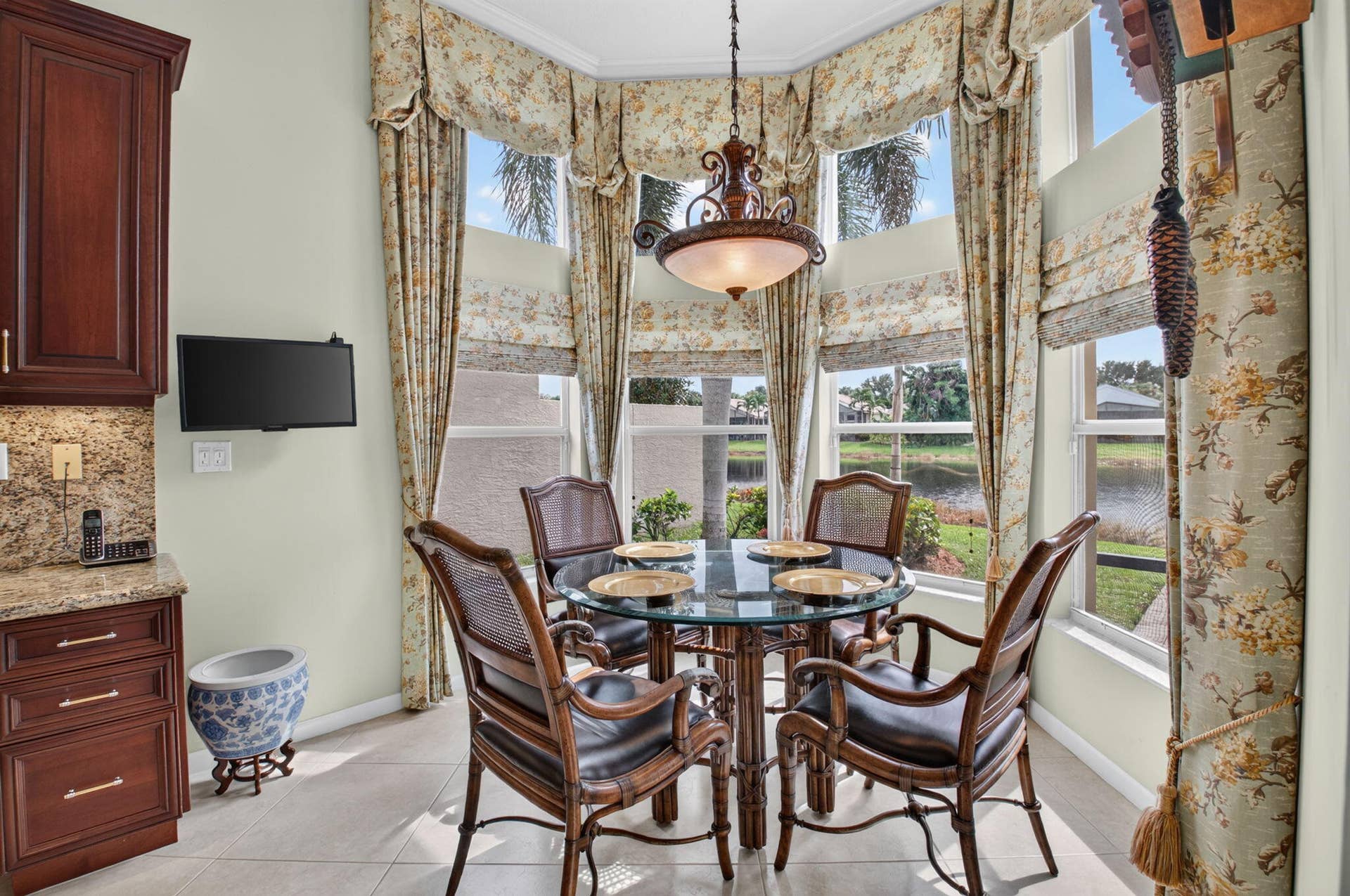6874 Venidita Beach Drive, Delray Beach, FL 33446 Bay window featuring expansive multi-pane glazing, stone-surfaced cabinetry, tile flooring, and a decorative pendant light fixture