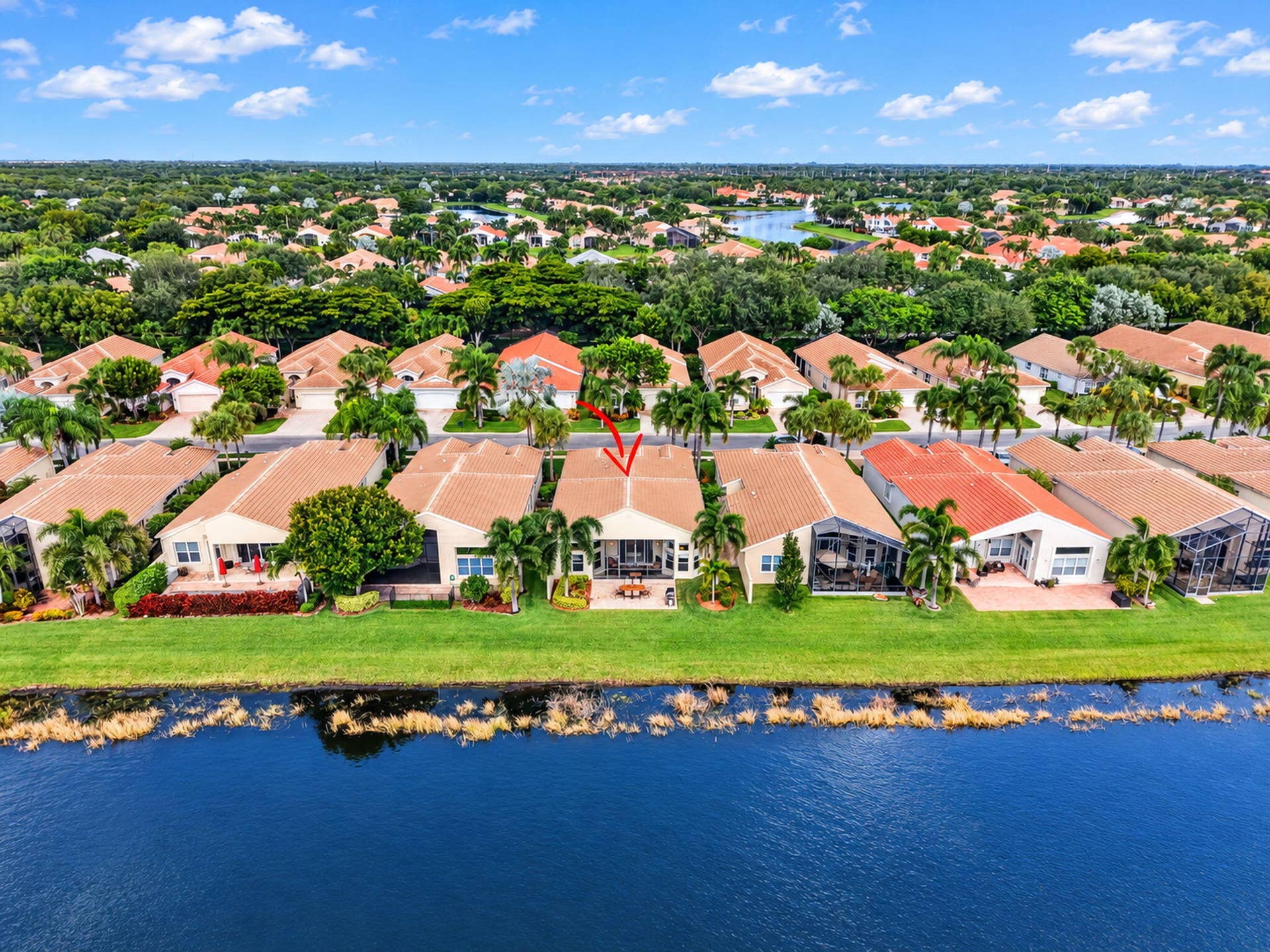 6874 Venidita Beach Drive, Delray Beach, FL 33446 Waterfront property featuring a tile roof, covered rear patio, and expansive lawn area