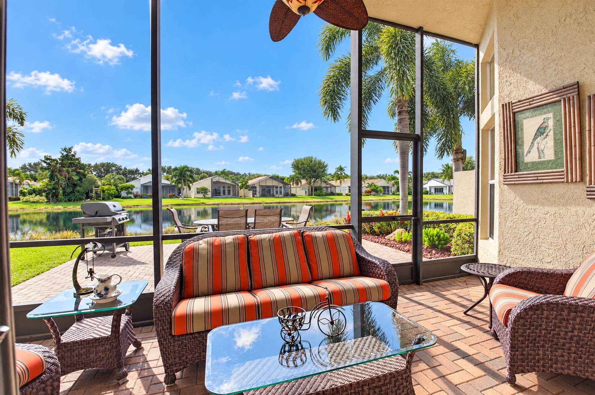 6874 Venidita Beach Drive, Delray Beach, FL 33446 Screened-in lanai with paver flooring, overhead ceiling fan, and stucco exterior walls, featuring an expansive water frontage