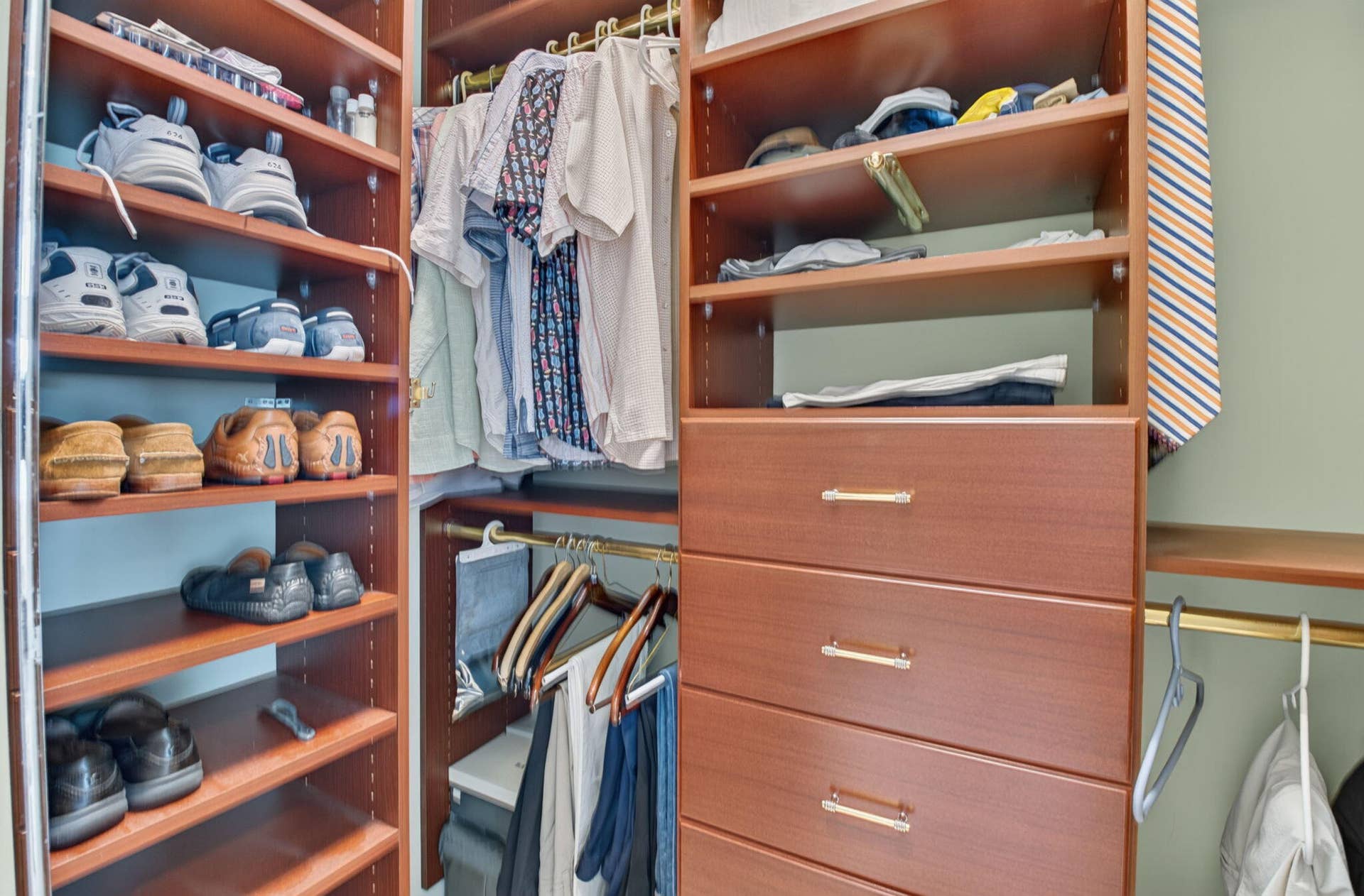 6874 Venidita Beach Drive, Delray Beach, FL 33446 Built-in wooden closet system featuring multiple open shelving units, integrated hanging rods, and a four-drawer dresser with metallic pulls