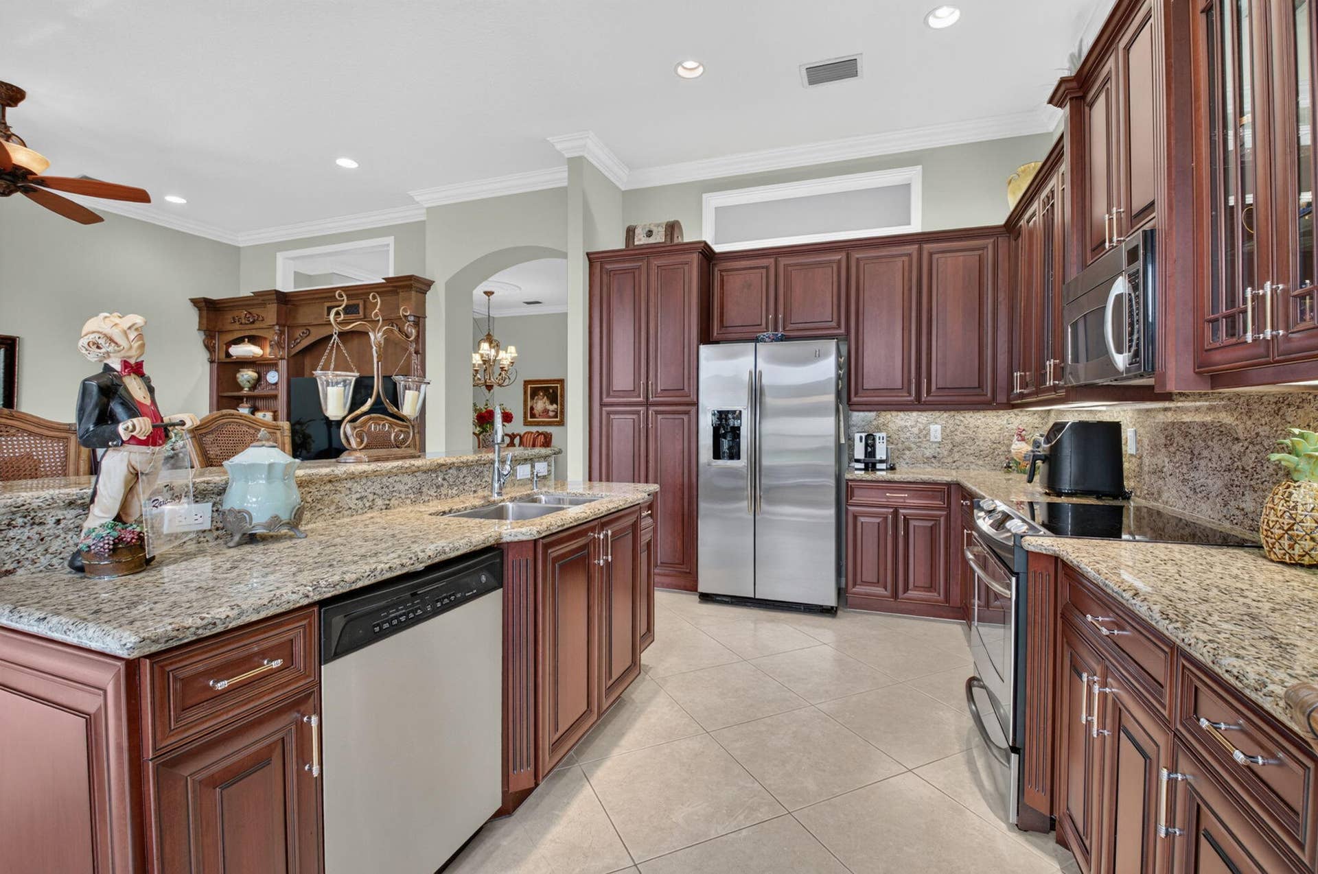 6874 Venidita Beach Drive, Delray Beach, FL 33446 Kitchen featuring raised-panel cherry cabinetry, stone countertops, stainless steel appliances, tile flooring, and recessed lighting