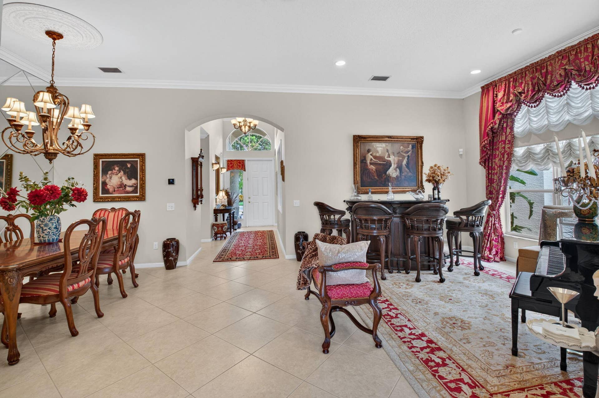 6874 Venidita Beach Drive, Delray Beach, FL 33446 Open-concept formal dining and entertaining space featuring neutral tile flooring, intricate ceiling medallion with multi-tiered chandelier, arched entryway, and crown molding