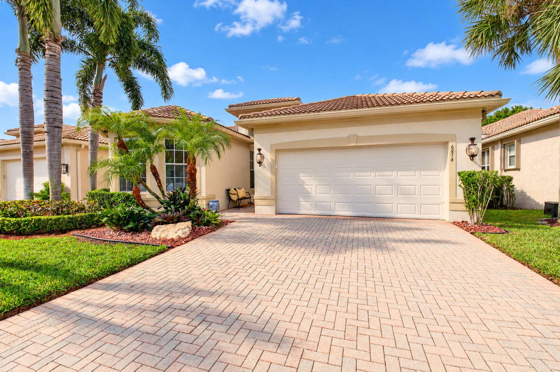 6874 Venidita Beach Drive, Delray Beach, FL 33446 Exterior facade featuring a tile roof, stucco finish, paved driveway, multi-panel garage door, and manicured landscaping