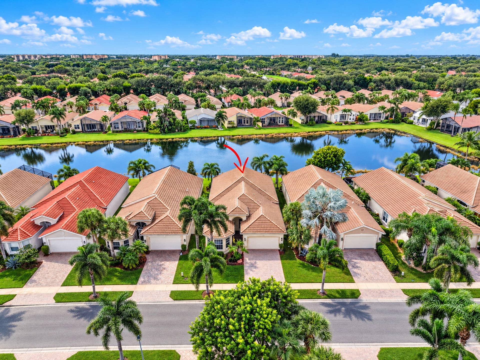 6874 Venidita Beach Drive, Delray Beach, FL 33446 Single-story residence featuring a tile roof, paved driveway, mature palm landscaping, and water frontage
