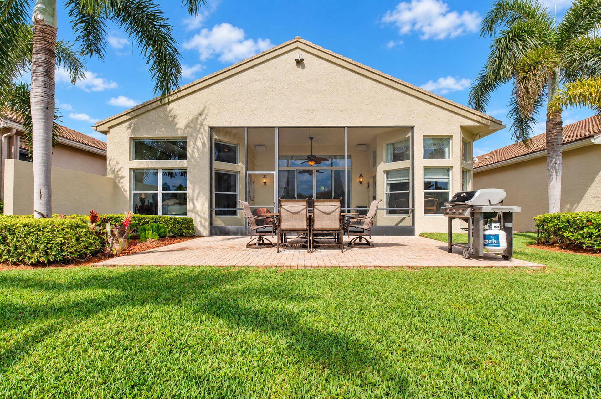 6874 Venidita Beach Drive, Delray Beach, FL 33446 Stucco exterior featuring a screened-in lanai, paver patio, and manicured lawn with room for a pool