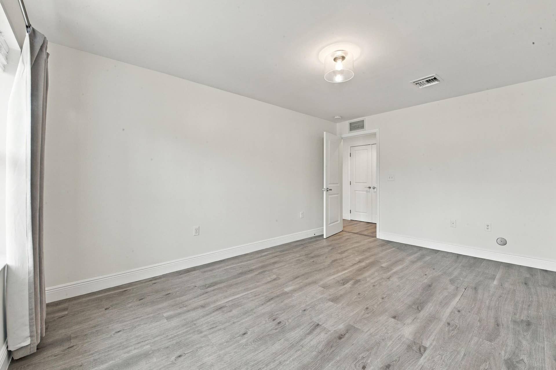 1066 NE 35TH Street, Oakland Park, FL 33334 Interior space featuring light-toned wood-finish flooring, neutral walls, a flush-mount circular light fixture, and a white interior door
