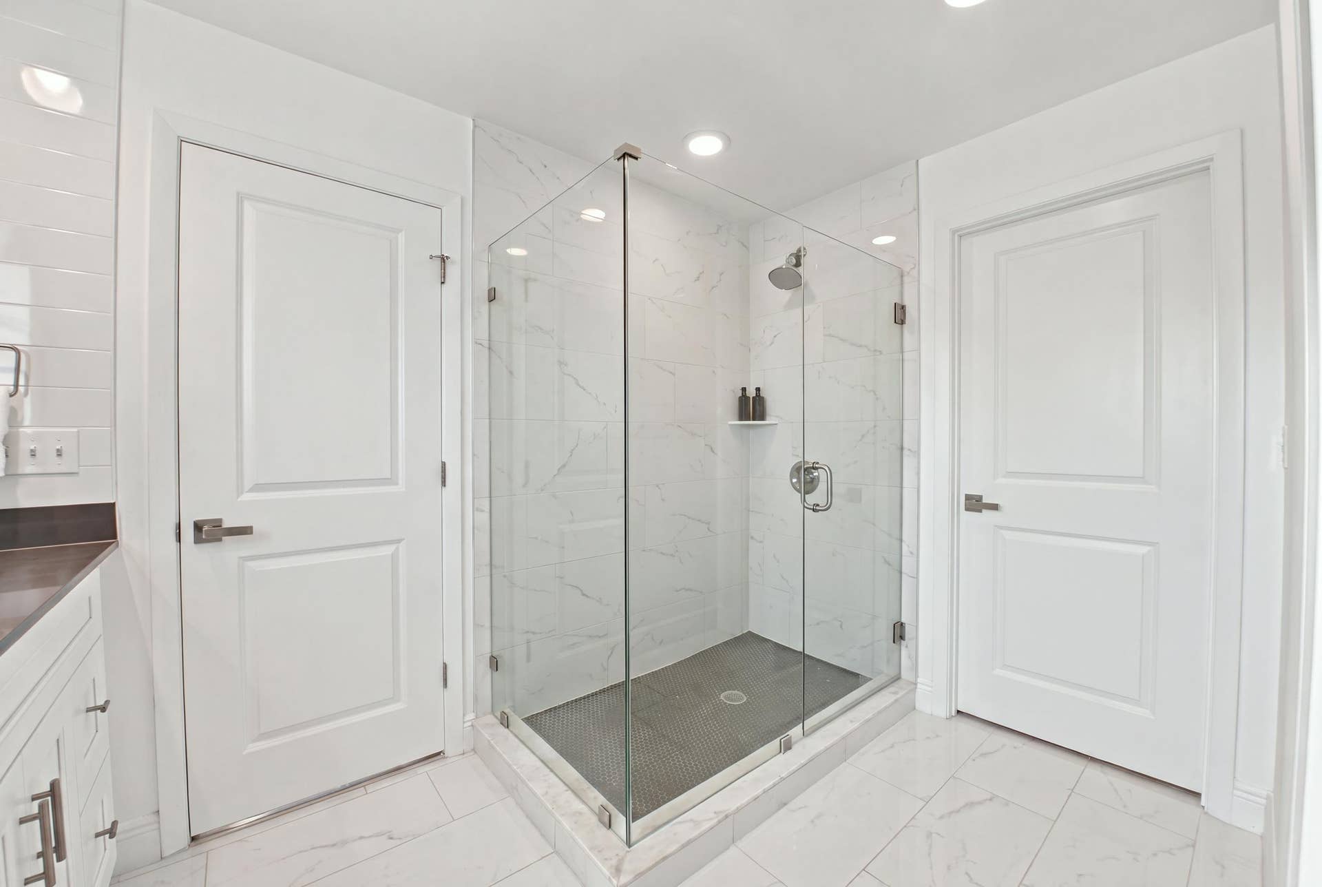1066 NE 35TH Street, Oakland Park, FL 33334 Glass-enclosed shower with stone-finish surround, recessed lighting, and built-in closet system featuring dark cabinetry with integrated shelving and drawers