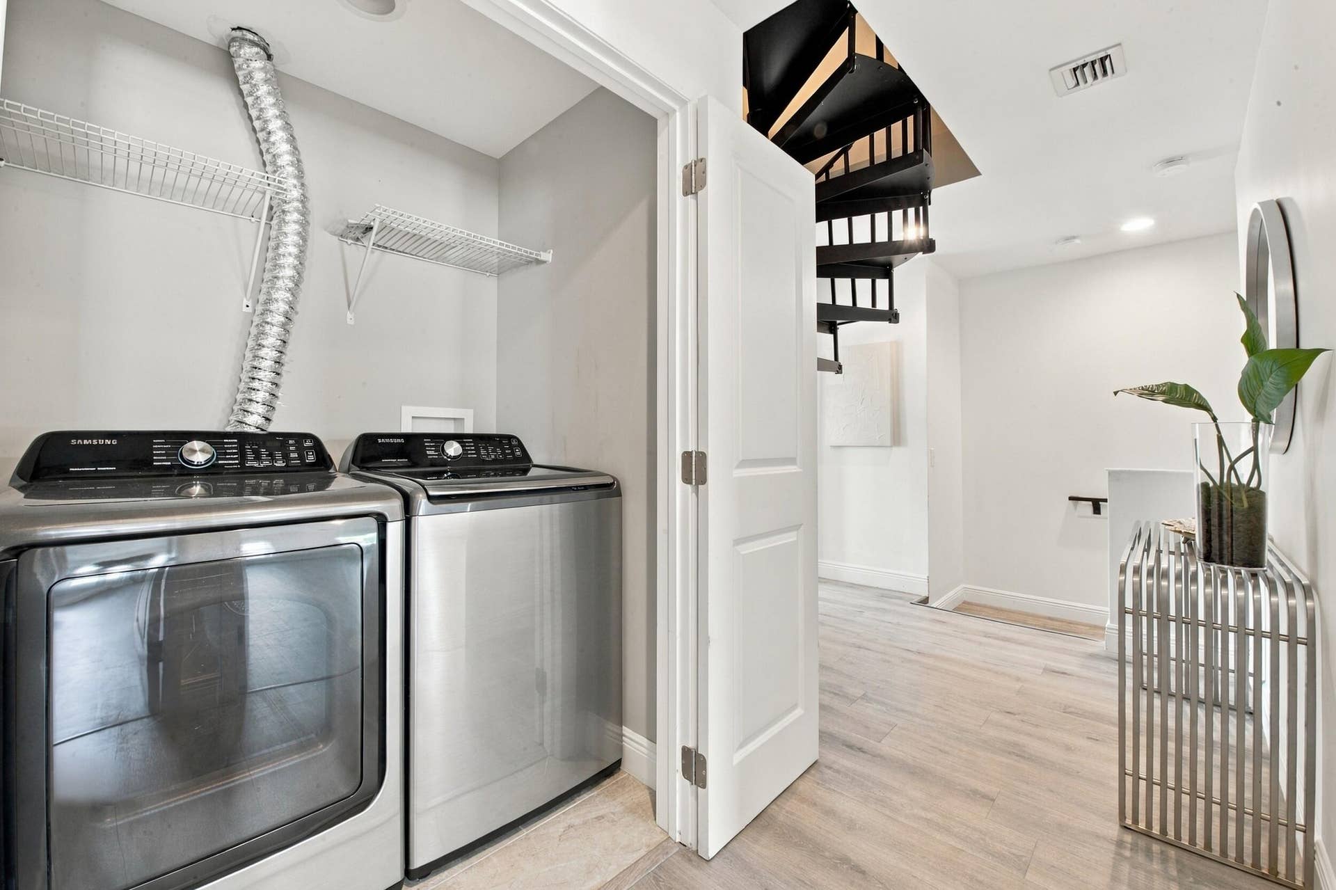 1066 NE 35TH Street, Oakland Park, FL 33334 Laundry area featuring stainless steel appliances and wire shelving, wood-finish flooring, and a spiral staircase with metal railings