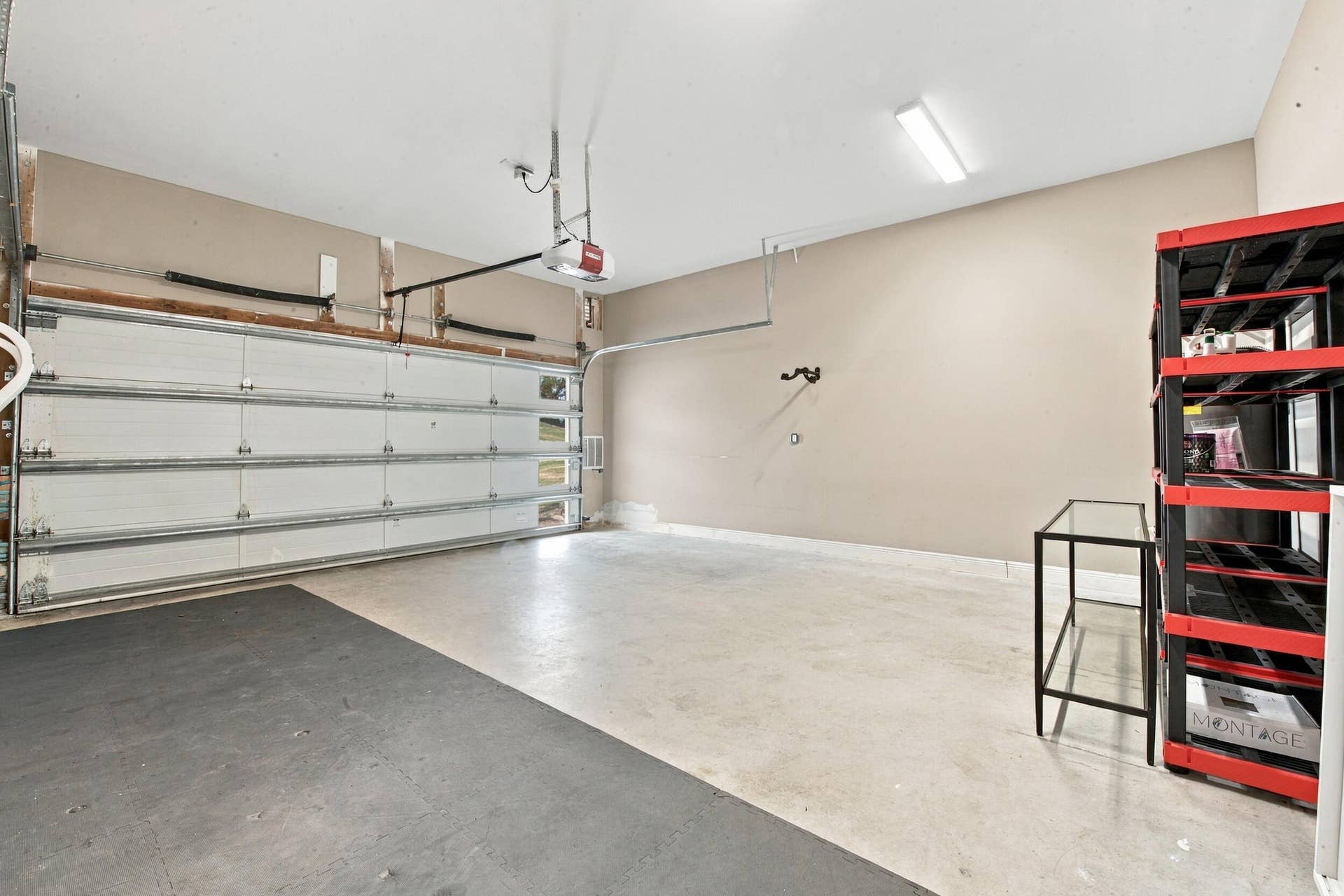 1066 NE 35TH Street, Oakland Park, FL 33334 Attached two-car garage featuring a sectional overhead door, concrete flooring, and linear overhead lighting