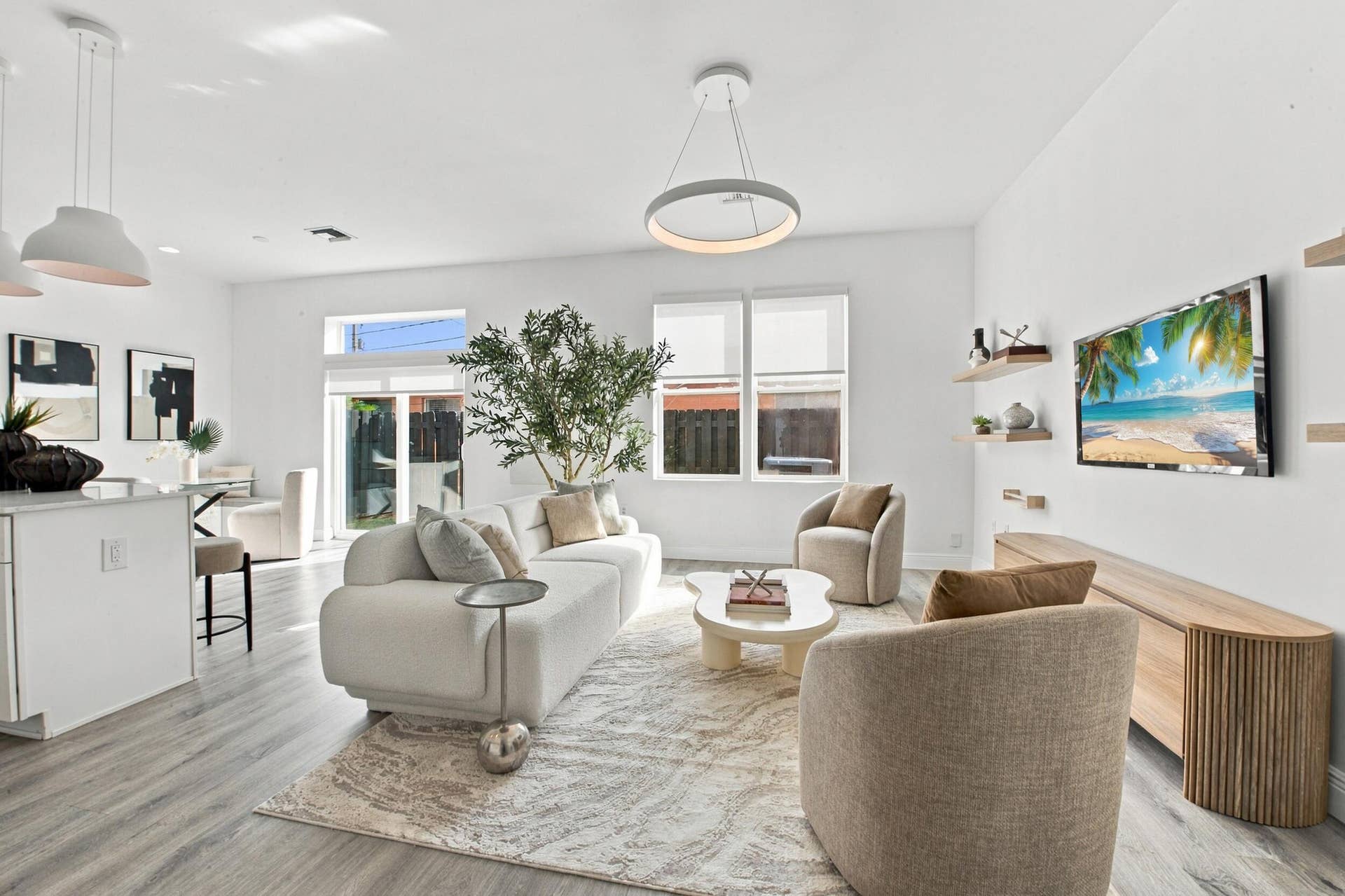 1066 NE 35TH Street, Oakland Park, FL 33334 Open-concept interior featuring wood-finish flooring, modern circular pendant lighting, wood-finish wall shelving, and large windows