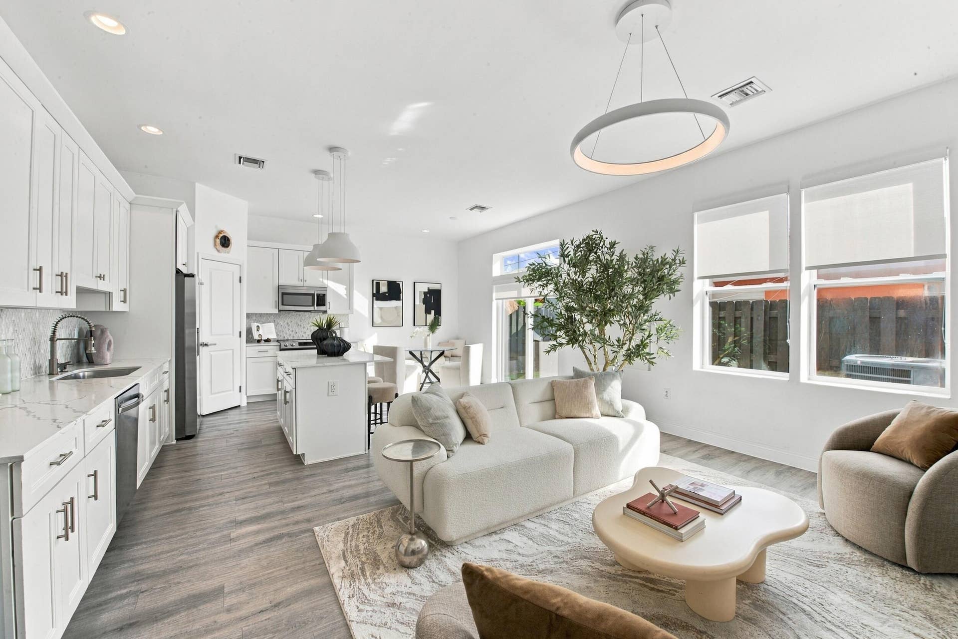1066 NE 35TH Street, Oakland Park, FL 33334 Open-concept kitchen featuring white shaker-style cabinetry, quartz countertops, a central island, wood-finish flooring, and a contemporary circular pendant light fixture