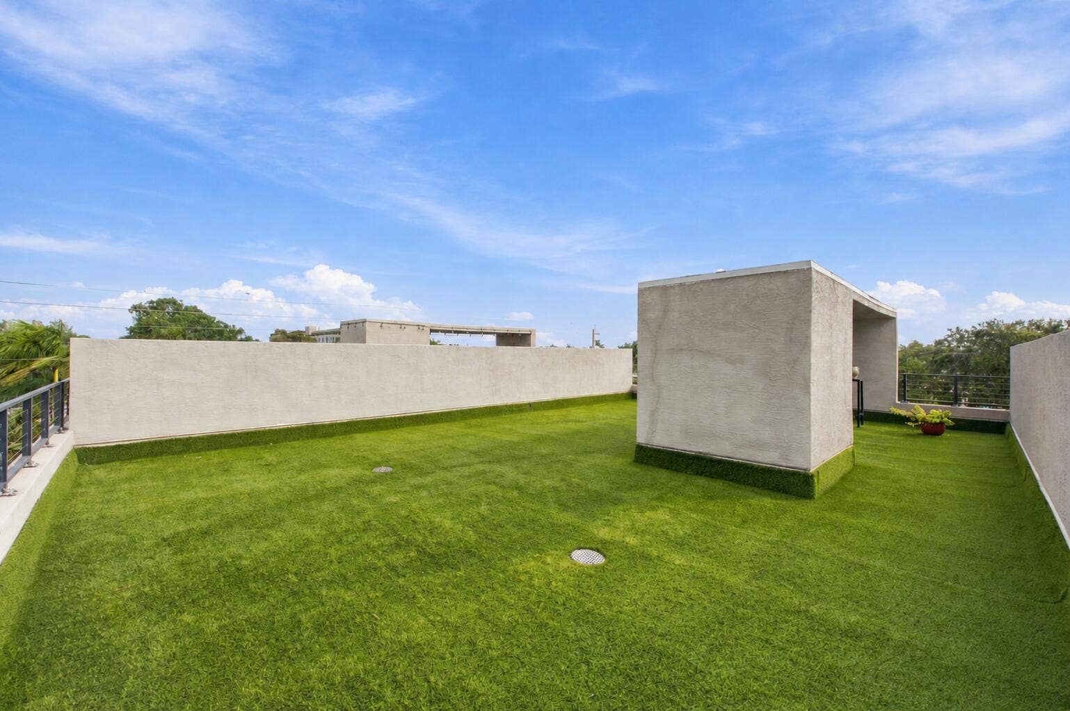1066 NE 35TH Street, Oakland Park, FL 33334 Expansive rooftop terrace featuring synthetic turf flooring, stucco-finished perimeter walls, and metal railings
