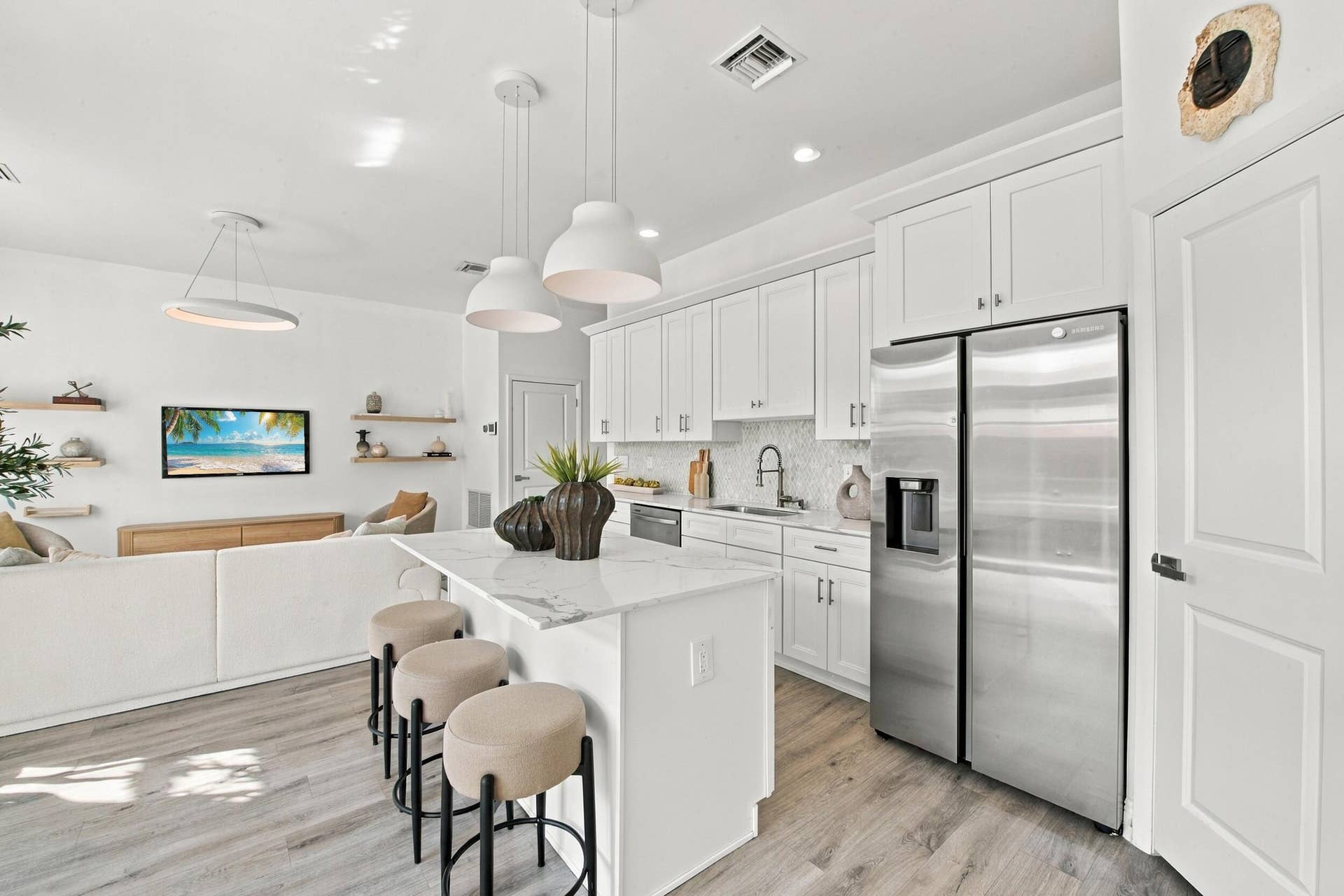 1066 NE 35TH Street, Oakland Park, FL 33334 Kitchen featuring white shaker-style cabinetry, stone-finish countertops, stainless steel appliances, a center island with pendant lighting, and wood-finish flooring