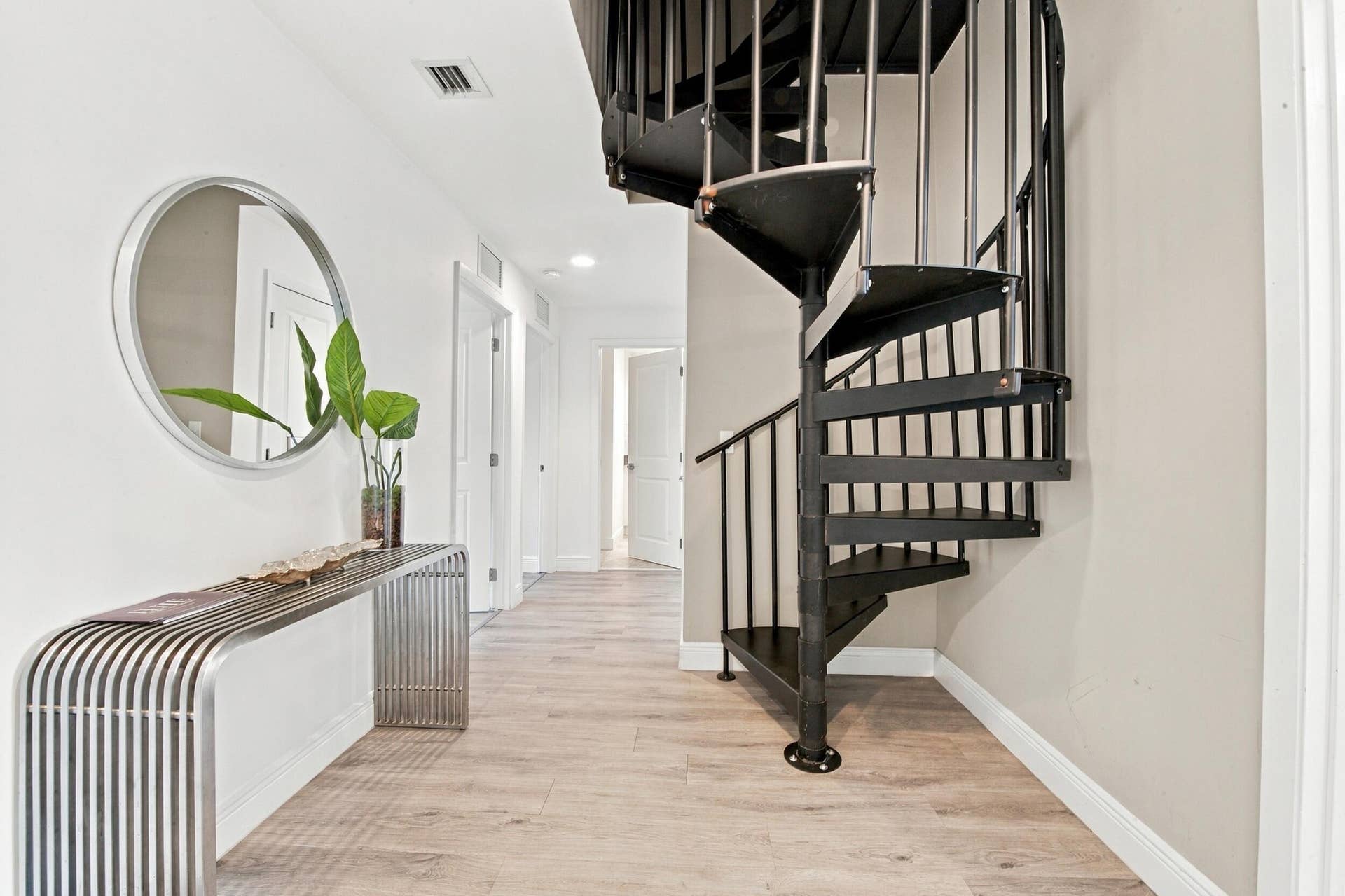 1066 NE 35TH Street, Oakland Park, FL 33334 Black metal spiral staircase featuring open risers and vertical balusters, complemented by wood-finish flooring