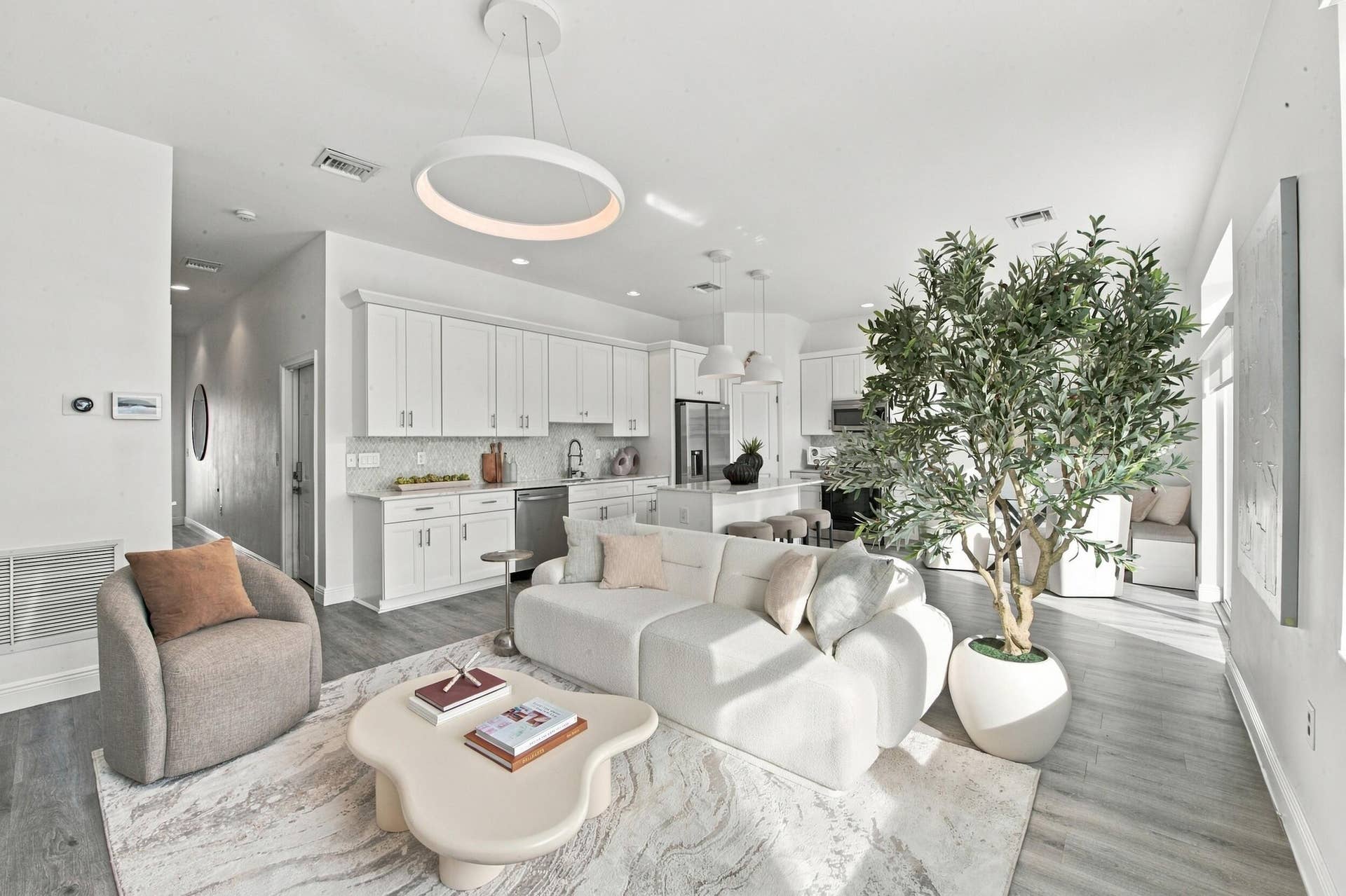 1066 NE 35TH Street, Oakland Park, FL 33334 Open-concept interior featuring wood-finish flooring, white shaker-style cabinetry, a central kitchen island, recessed lighting, and a modern circular pendant light fixture