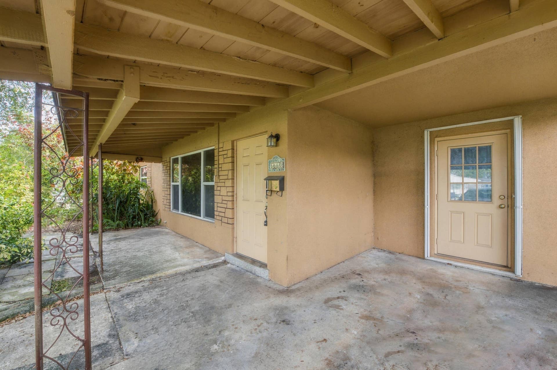 6660 FREEDOM Street, Hollywood, FL 33024 Covered entryway featuring a concrete porch, exposed beam ceiling, decorative metal support post, and dual exterior doors with multi-pane glass detailing