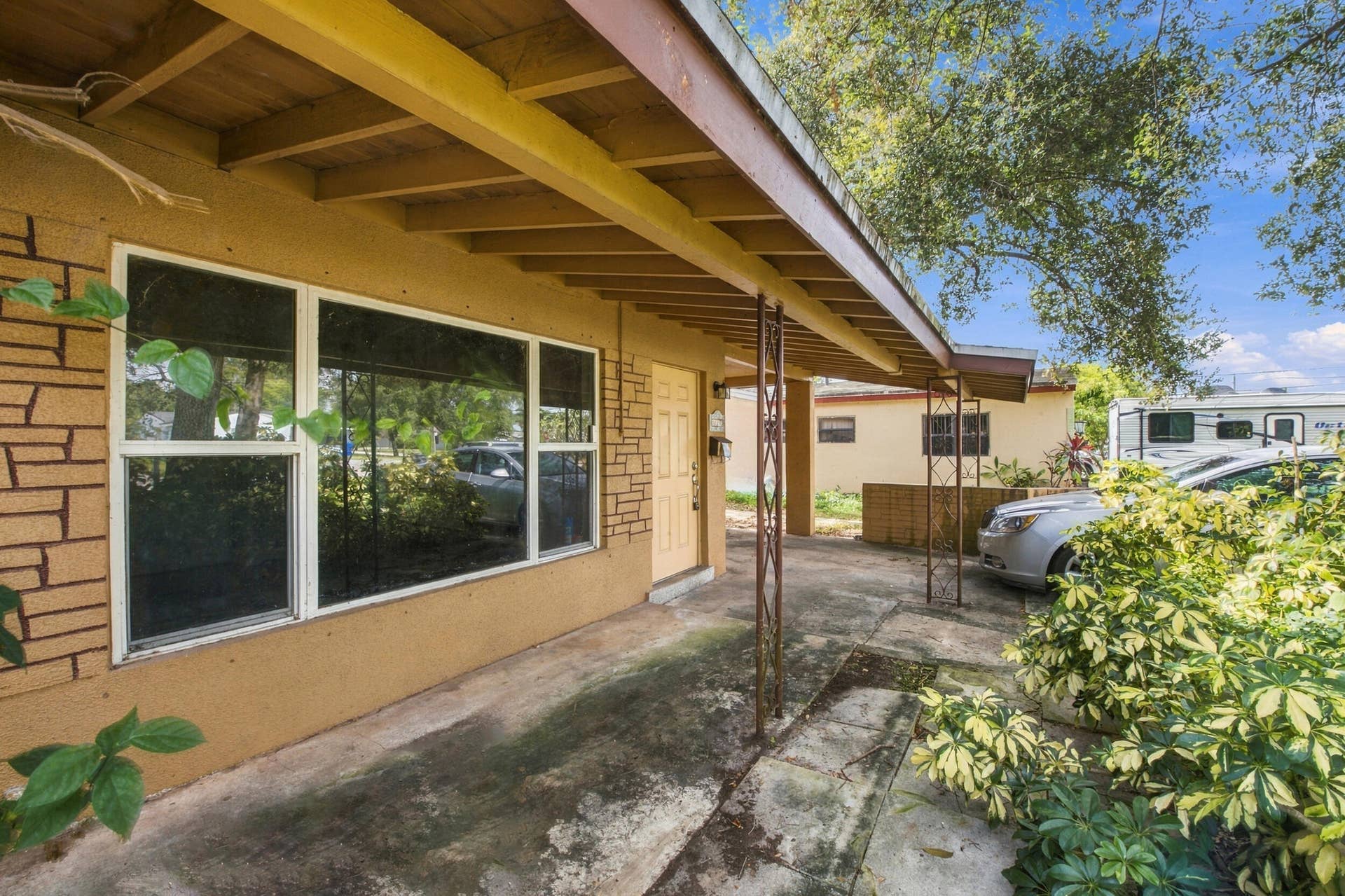 6660 FREEDOM Street, Hollywood, FL 33024 Exterior facade featuring textured stucco, stone-veneer accents, a covered concrete porch, and metal support posts