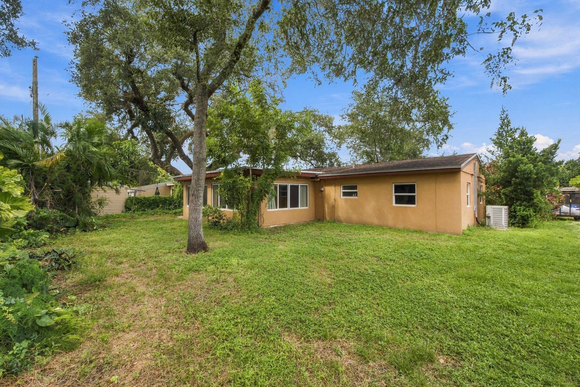 6660 FREEDOM Street, Hollywood, FL 33024 Single-story stucco exterior featuring multi-pane windows and mature trees set within a grass lawn