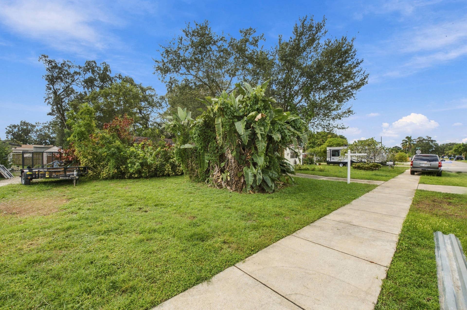 6660 FREEDOM Street, Hollywood, FL 33024 Expansive corner lot featuring mature tropical landscaping, established trees, and a concrete sidewalk
