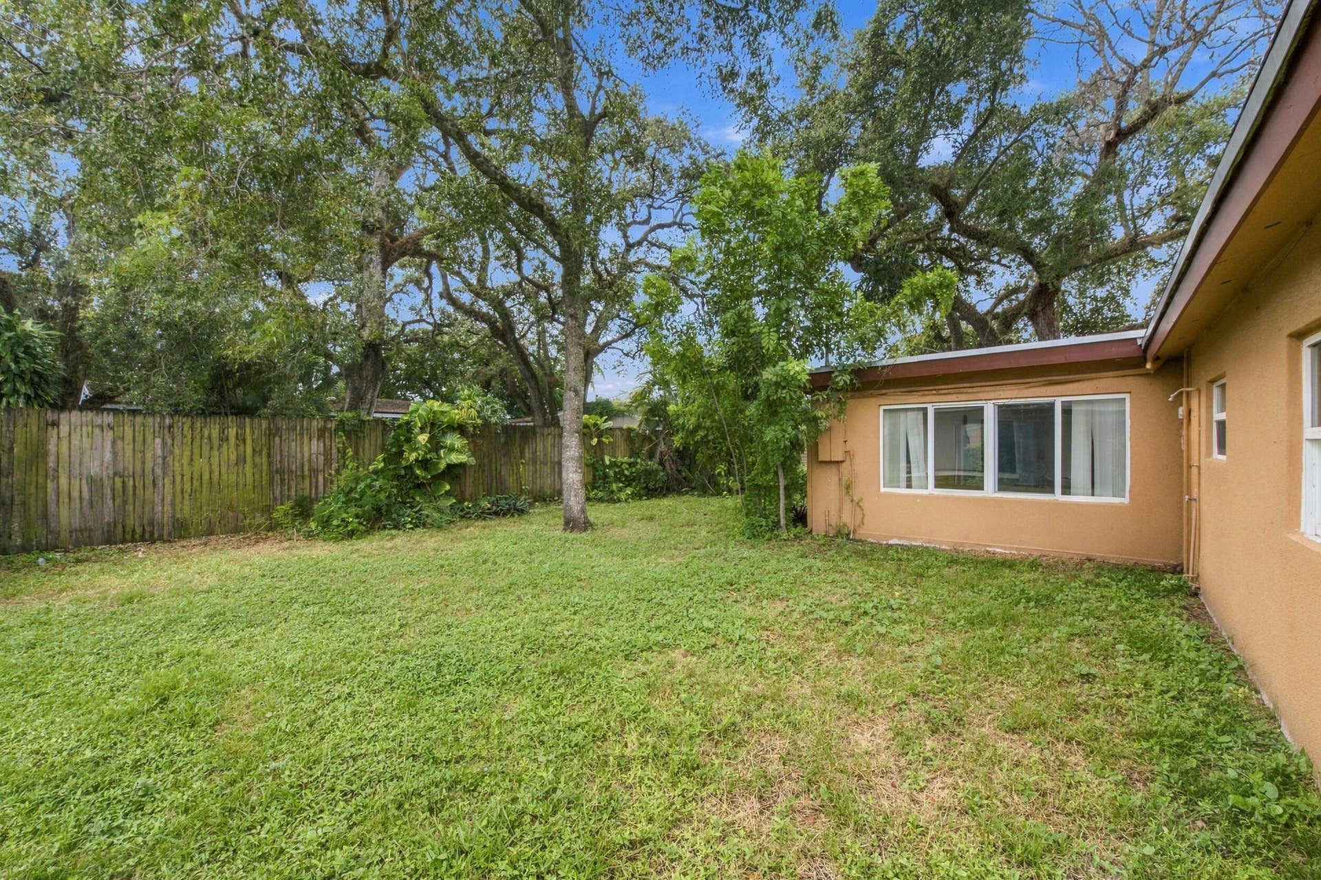 6660 FREEDOM Street, Hollywood, FL 33024 Backyard featuring a grass lawn, mature trees, and a wooden privacy fence