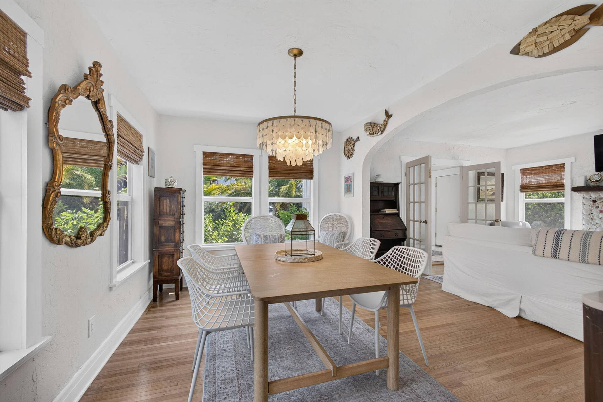 Dining room, seating for 6 featuring wood-finish flooring, a tiered shell-style chandelier, arched architectural detailing, and dual French doors with glass panes